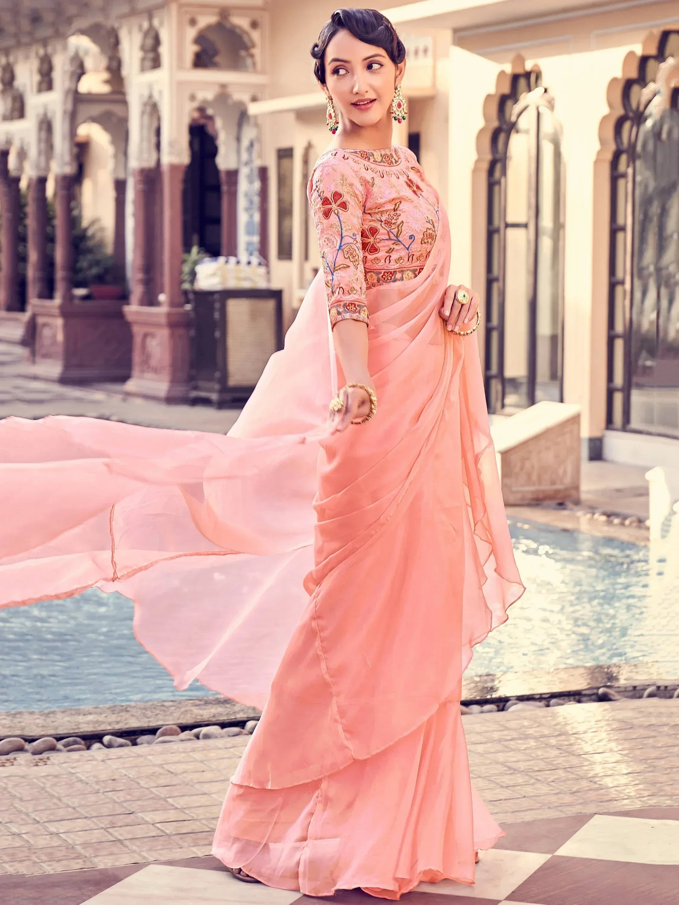 Woman in pink embroidered saree with floral design, traditional Indian ethnic wear, palace courtyard setting