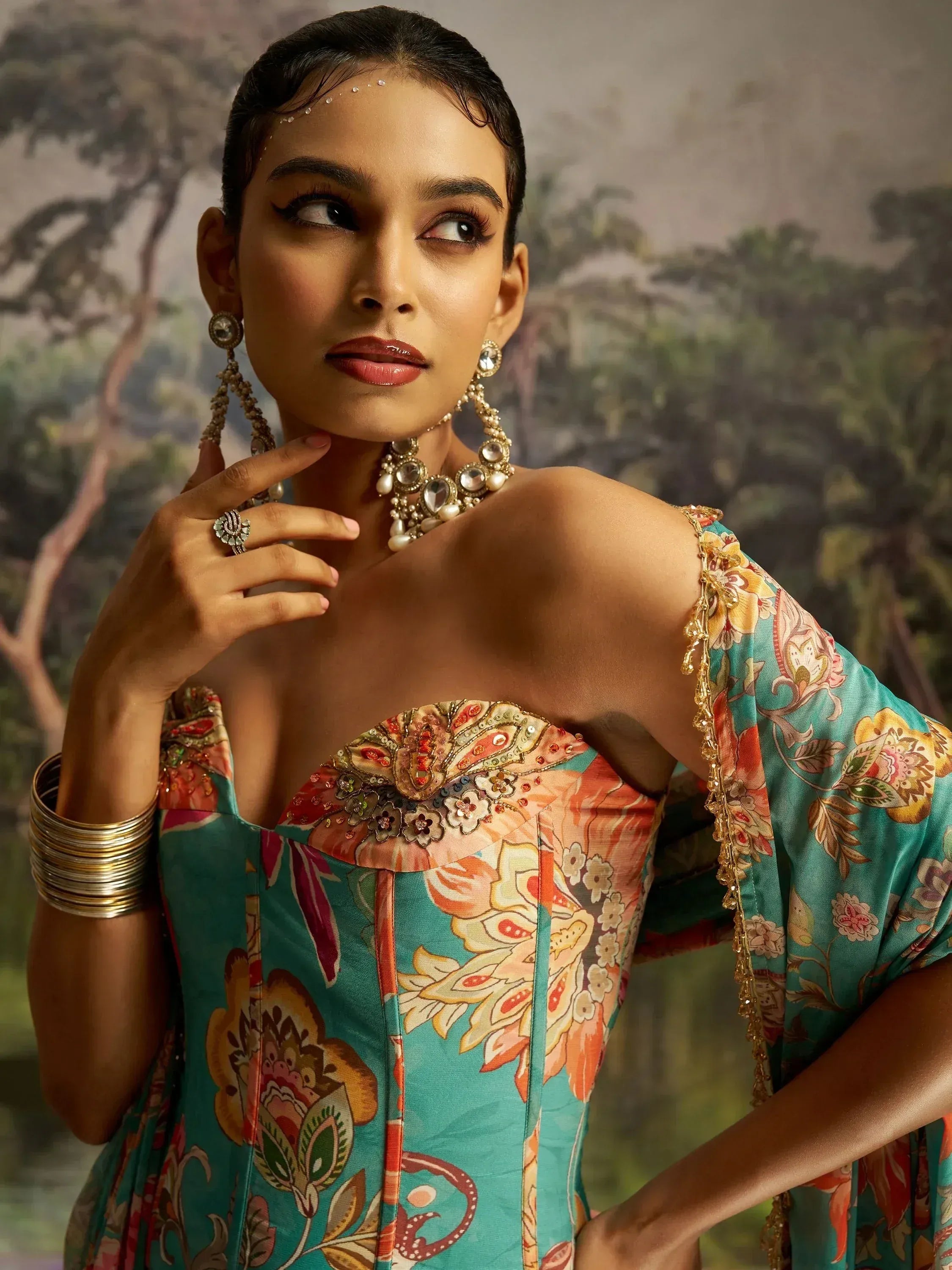 Woman in floral printed ethnic gown with gold jewelry, perfect for Indian occasions