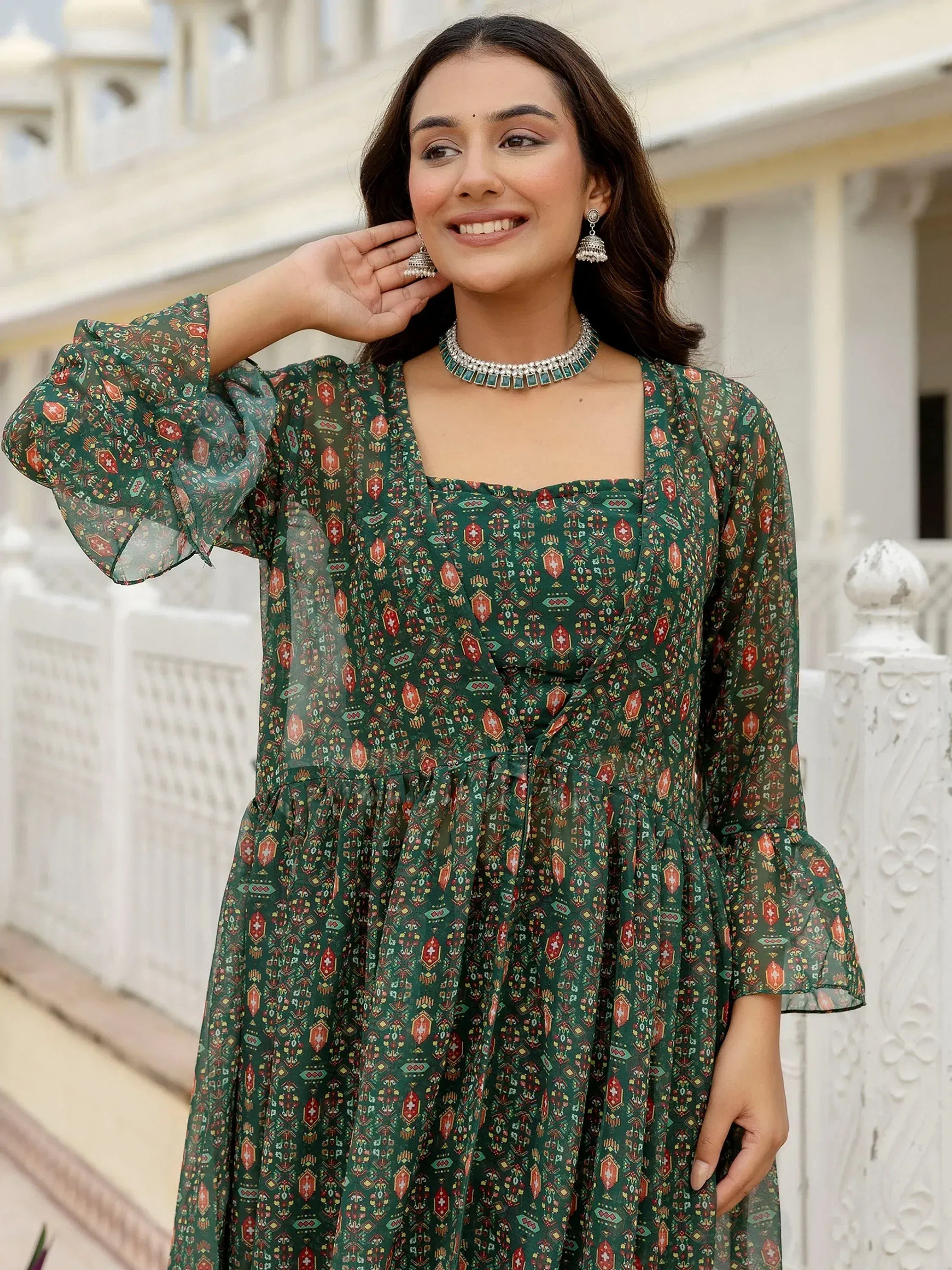 Green printed ethnic gown with puff sleeves, square neck, and flared skirt, styled with traditional jewelry.