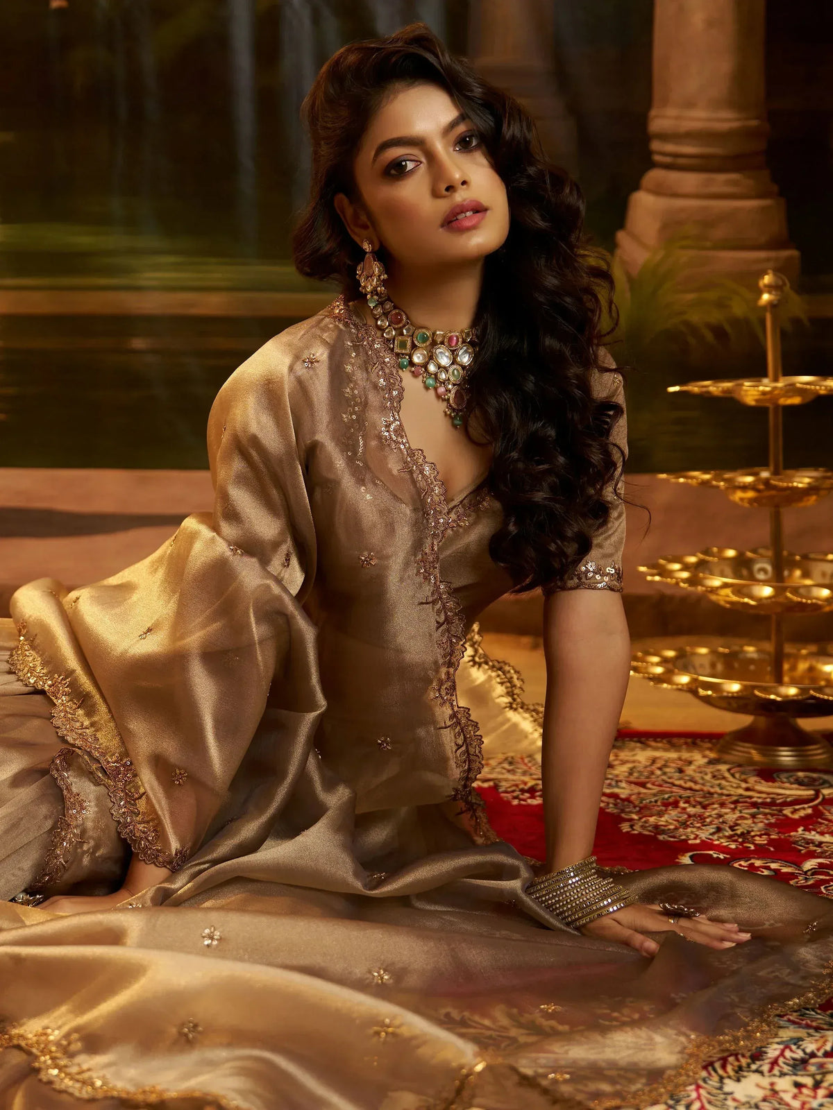 Elegant woman in gold embroidered ethnic gown with traditional jewelry, perfect for Indian weddings and festive occasions.