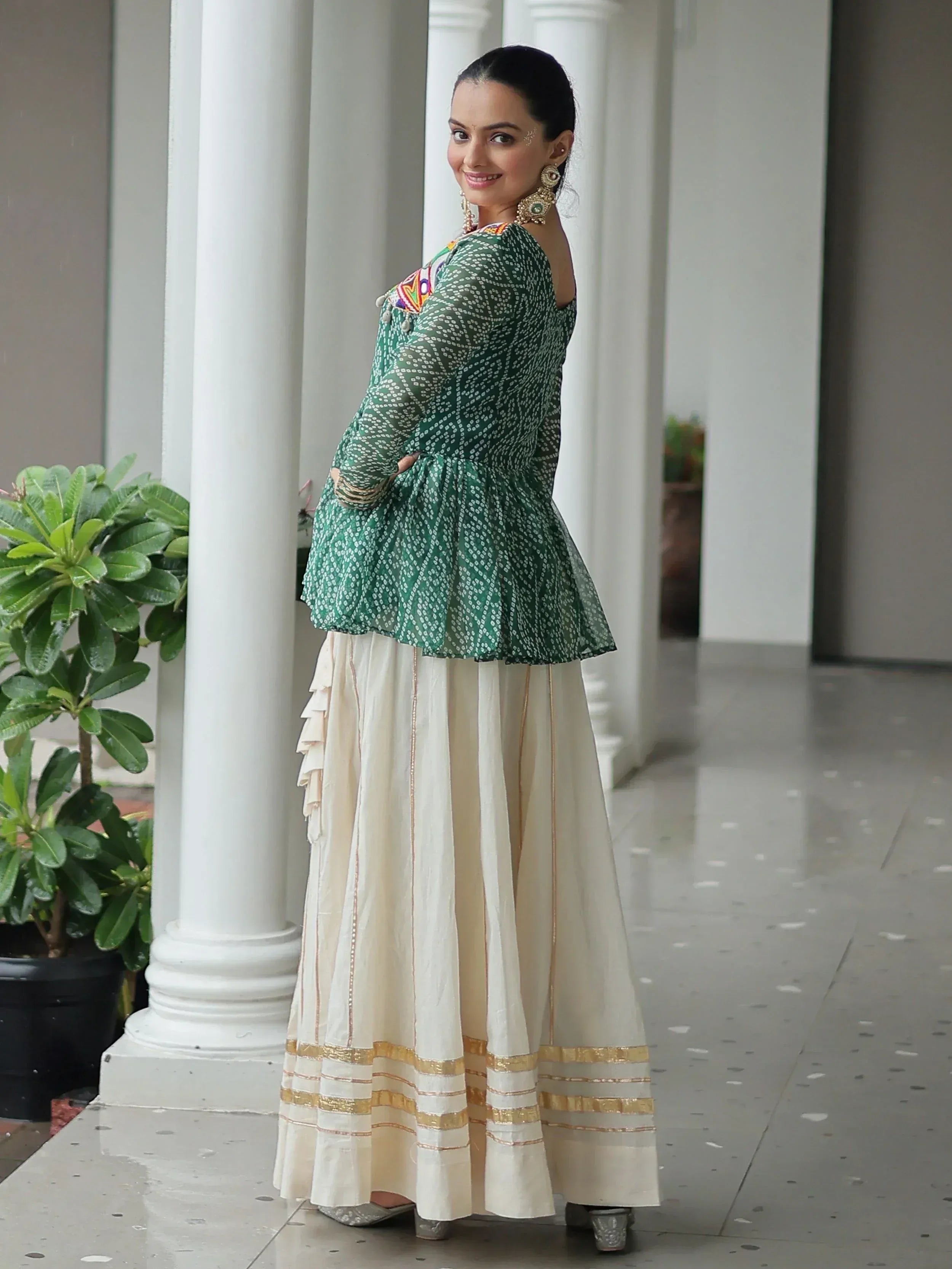 Woman in green printed peplum top and cream ruffled skirt, Indian ethnic wear