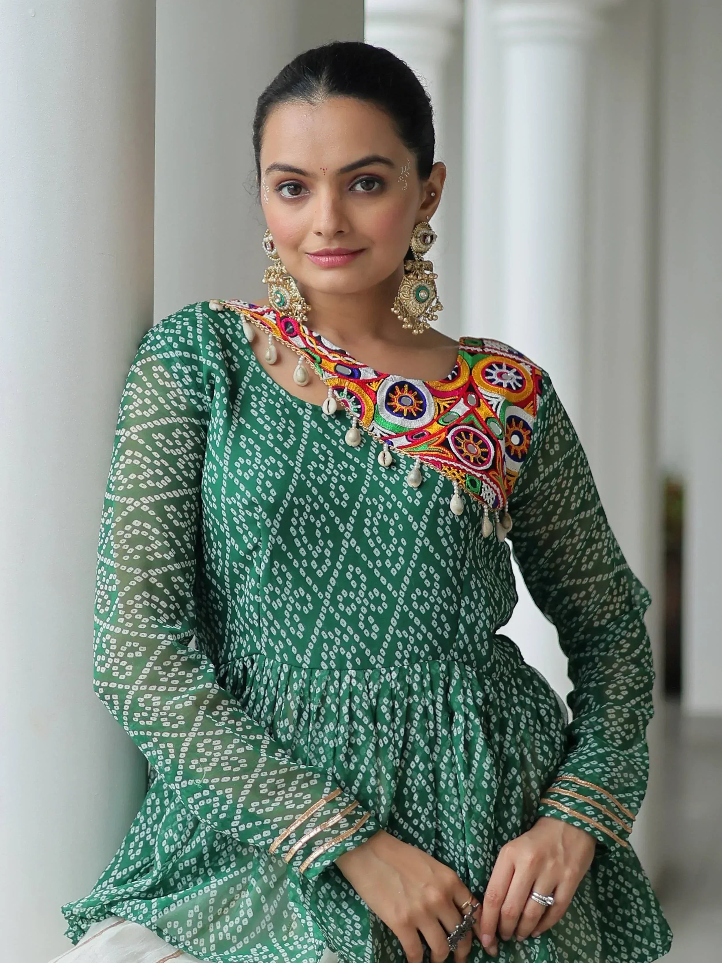 Green ethnic kurti with colorful mirror embroidery and pearl detailing, paired with statement earrings