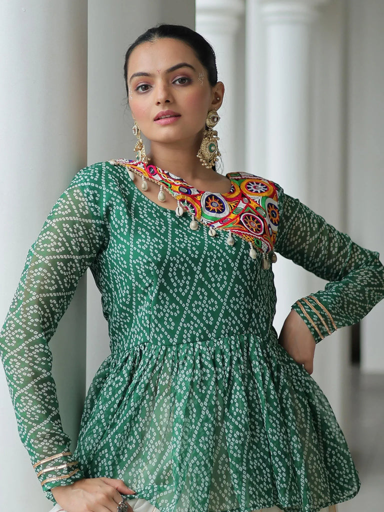 Green printed ethnic kurti with colorful embroidery and mirror work, paired with statement earrings.