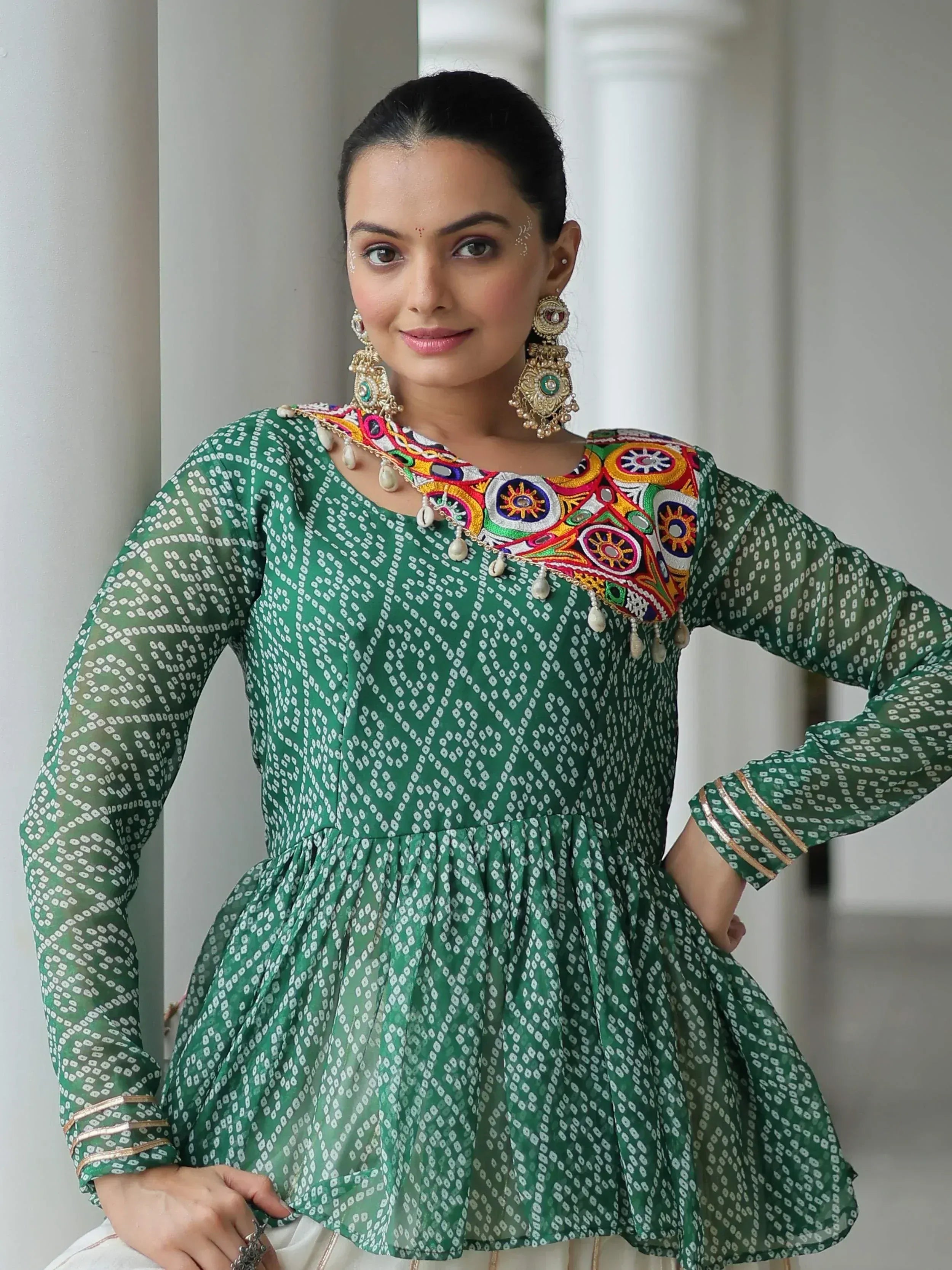 Green printed ethnic kurti with colorful mirror embroidery and gold trim, paired with statement earrings.
