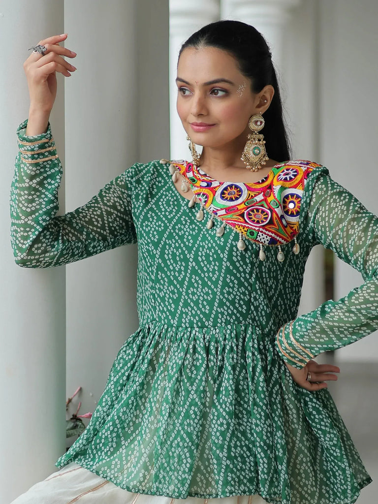 Green printed ethnic kurta with colorful mirror embroidery and gold trim, paired with statement earrings.