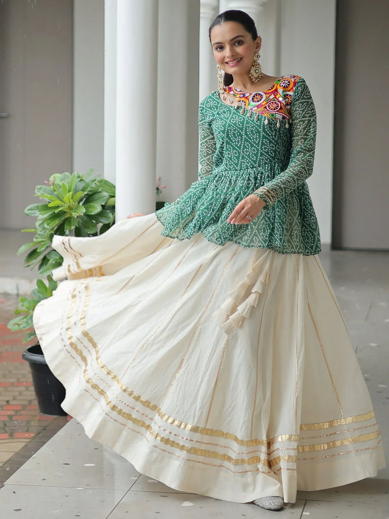 Woman in green embroidered top and cream pleated skirt with gold trim, Indian ethnic wear