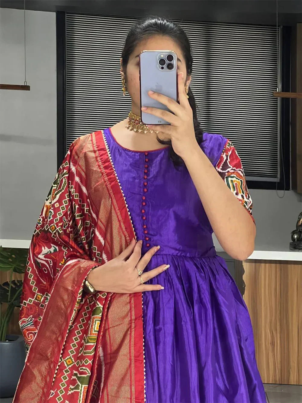 Woman in a purple ethnic gown with printed red dupatta and gold jewelry