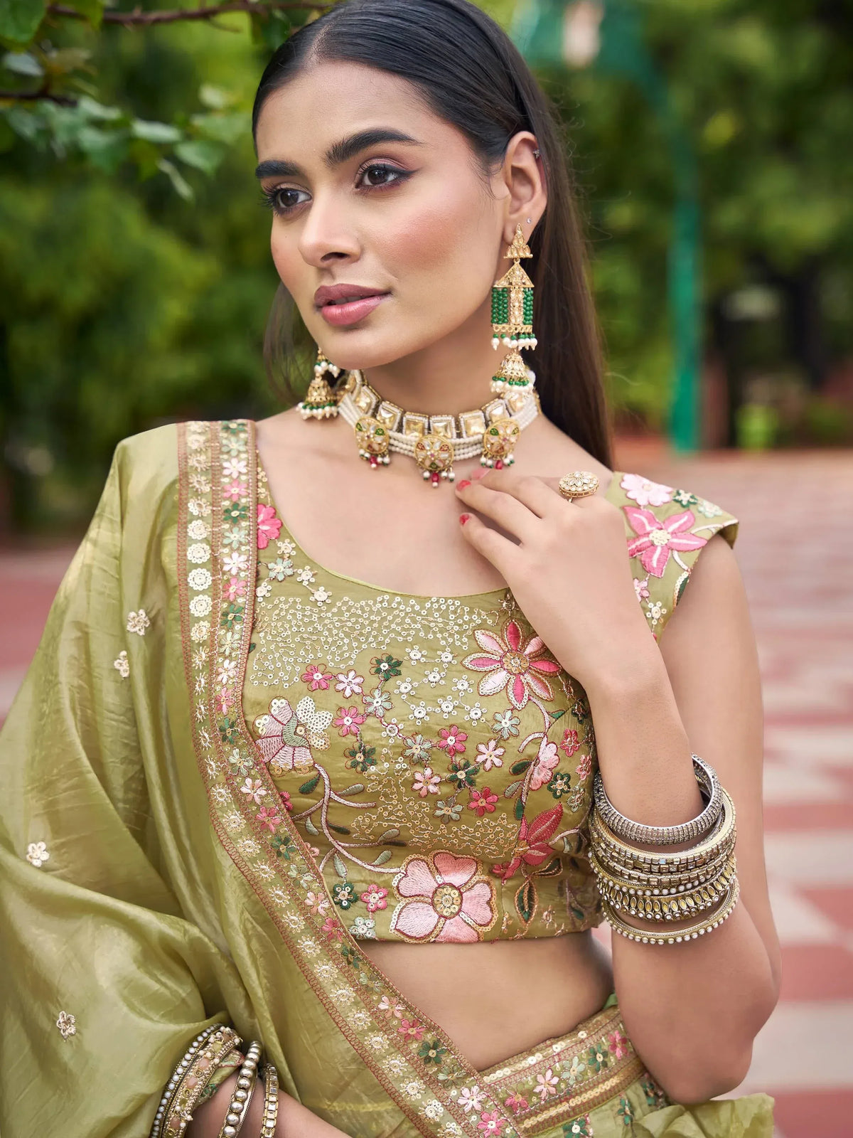 Olive green floral embroidered lehenga choli with gold jewelry, perfect for Indian ethnic wear occasions.