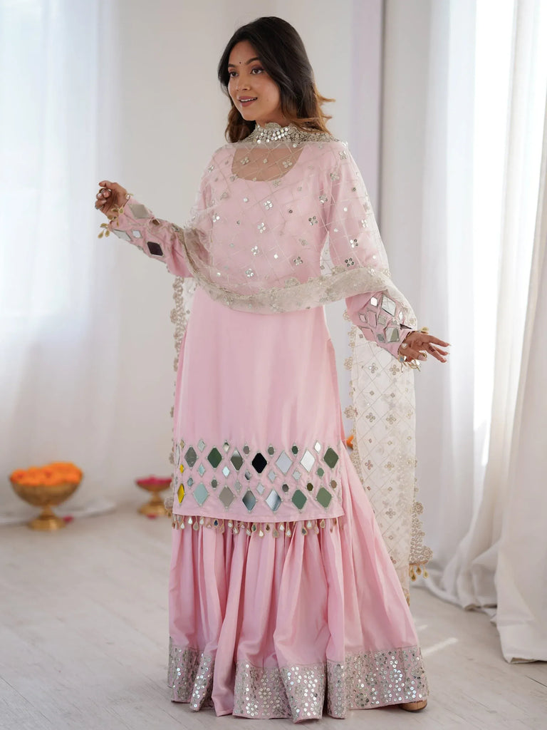 Woman wearing a light pink designer salwar kameez with mirror work and a matching dupatta