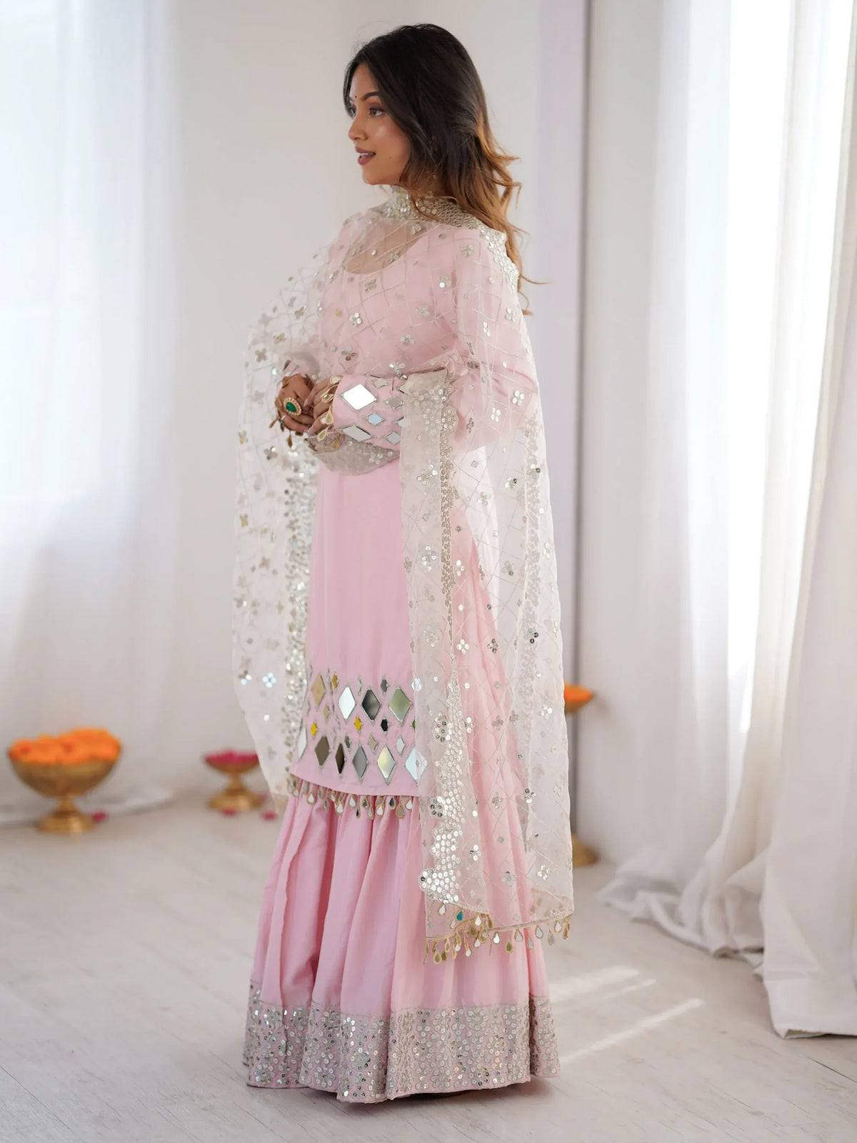 Woman wearing a pink designer salwar kameez with mirror work and a sheer dupatta