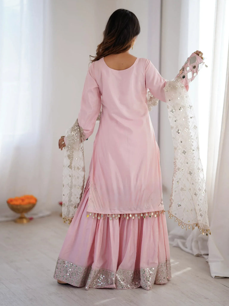 Woman wearing a baby pink ethnic salwar kameez with sequin work and a matching dupatta