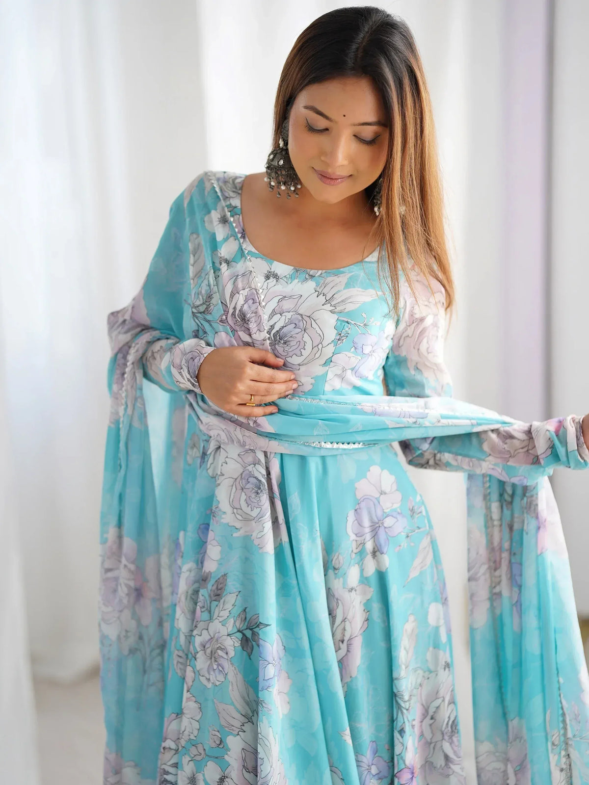 Woman in turquoise floral ethnic gown with long sleeves and silver embellishments