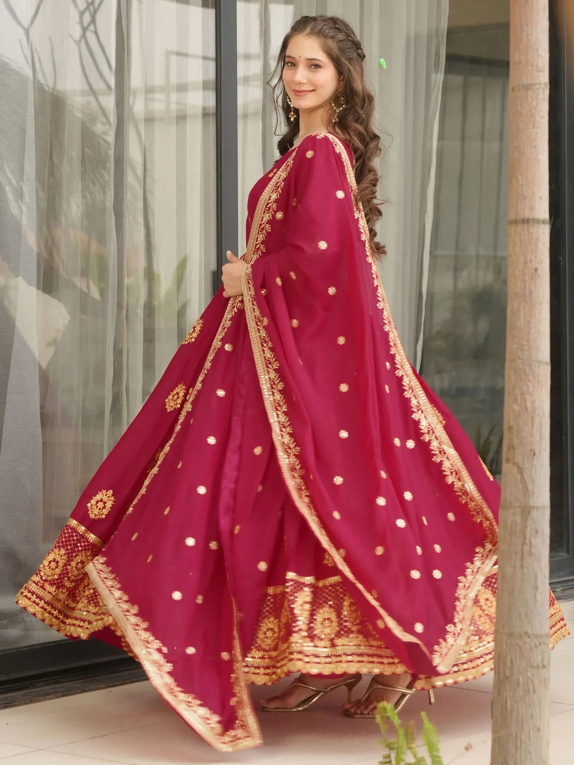 Woman in maroon Indian ethnic wear with gold embroidery, perfect for weddings or festivals