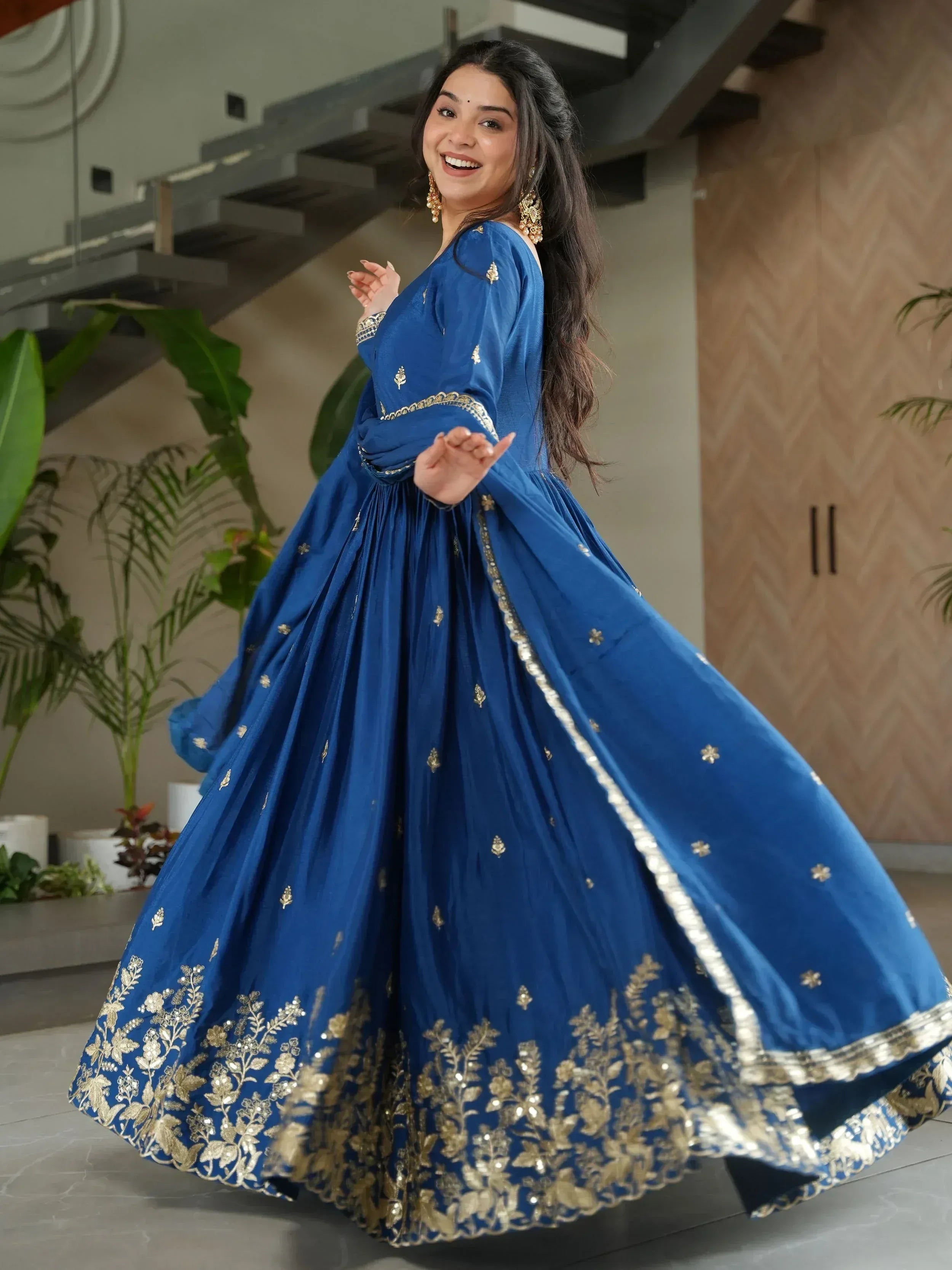 Woman in royal blue ethnic gown with gold embroidery, perfect for Indian festive occasions and weddings.