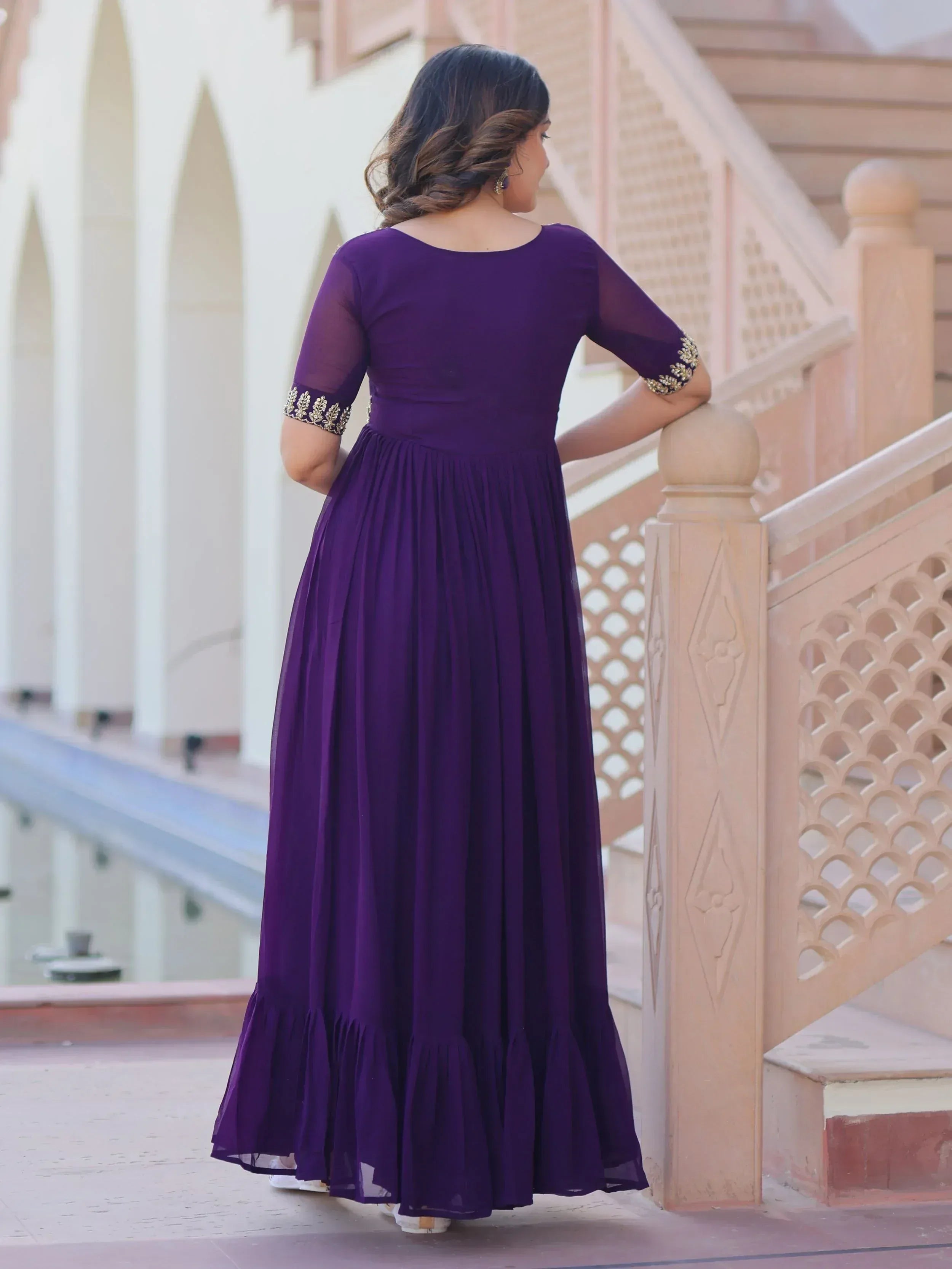 Purple ethnic gown with gold embroidery, pleated skirt, and sheer sleeves, perfect for Indian occasions.