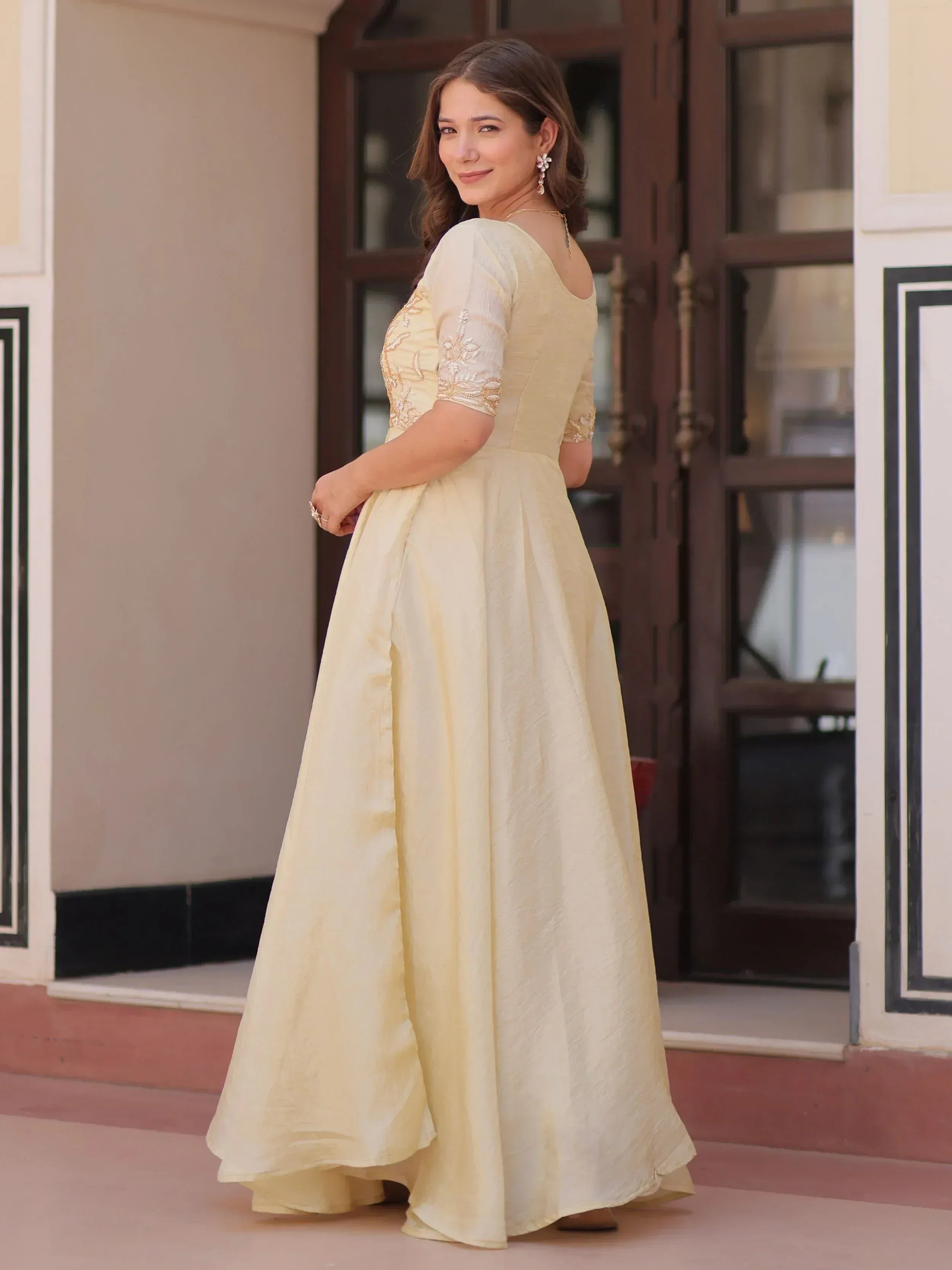 Elegant cream ethnic gown with embroidered sleeves, perfect for Indian weddings and festive occasions.