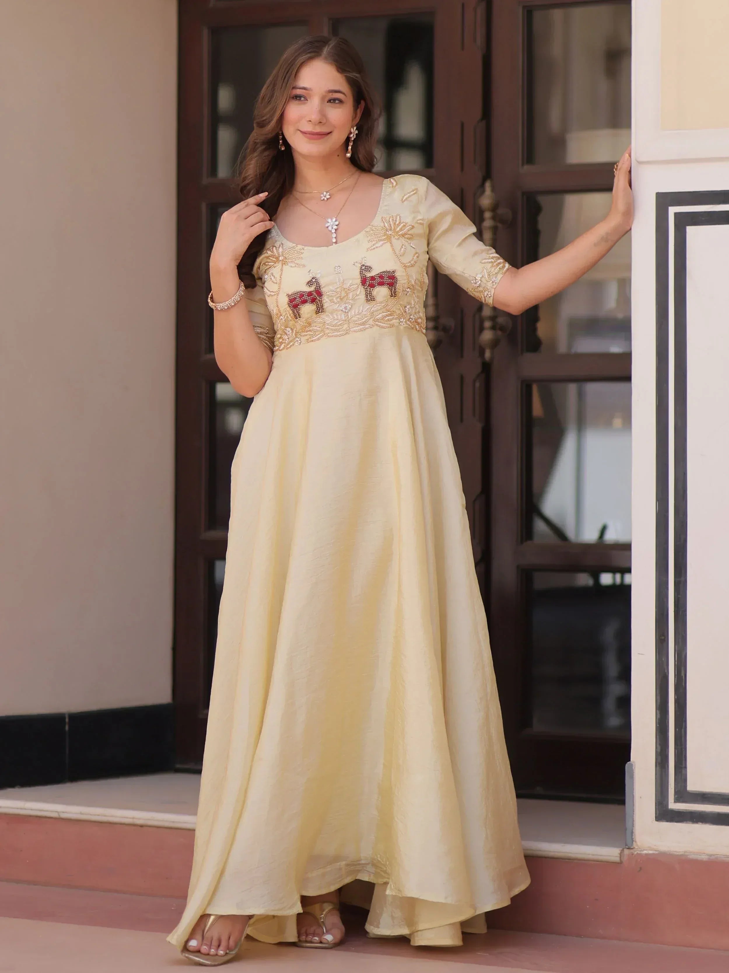 Elegant cream ethnic gown with embroidered deer motifs, perfect for Indian occasions and festive wear.