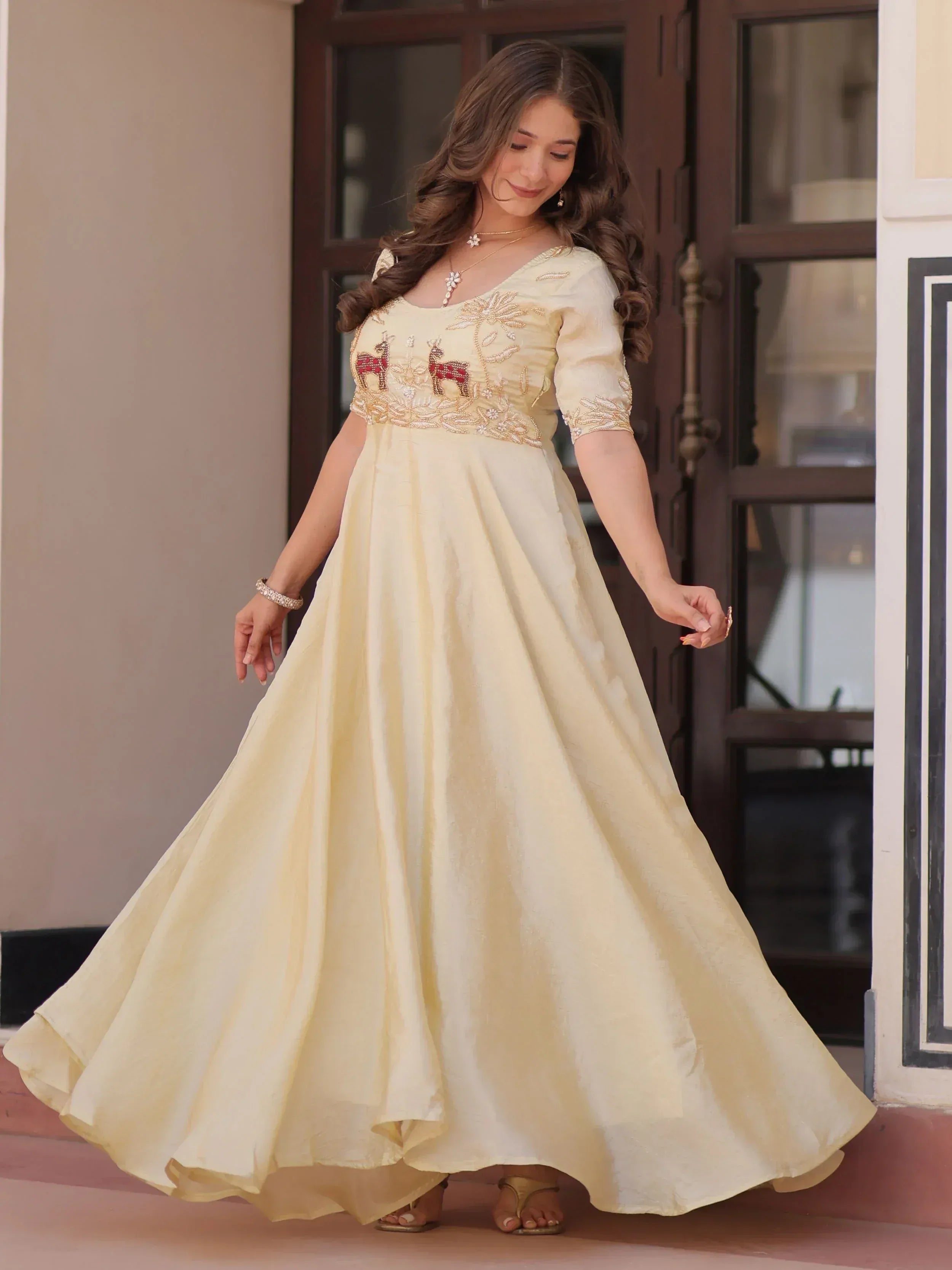 Elegant cream ethnic gown with deer embroidery, perfect for Indian festive occasions and weddings.