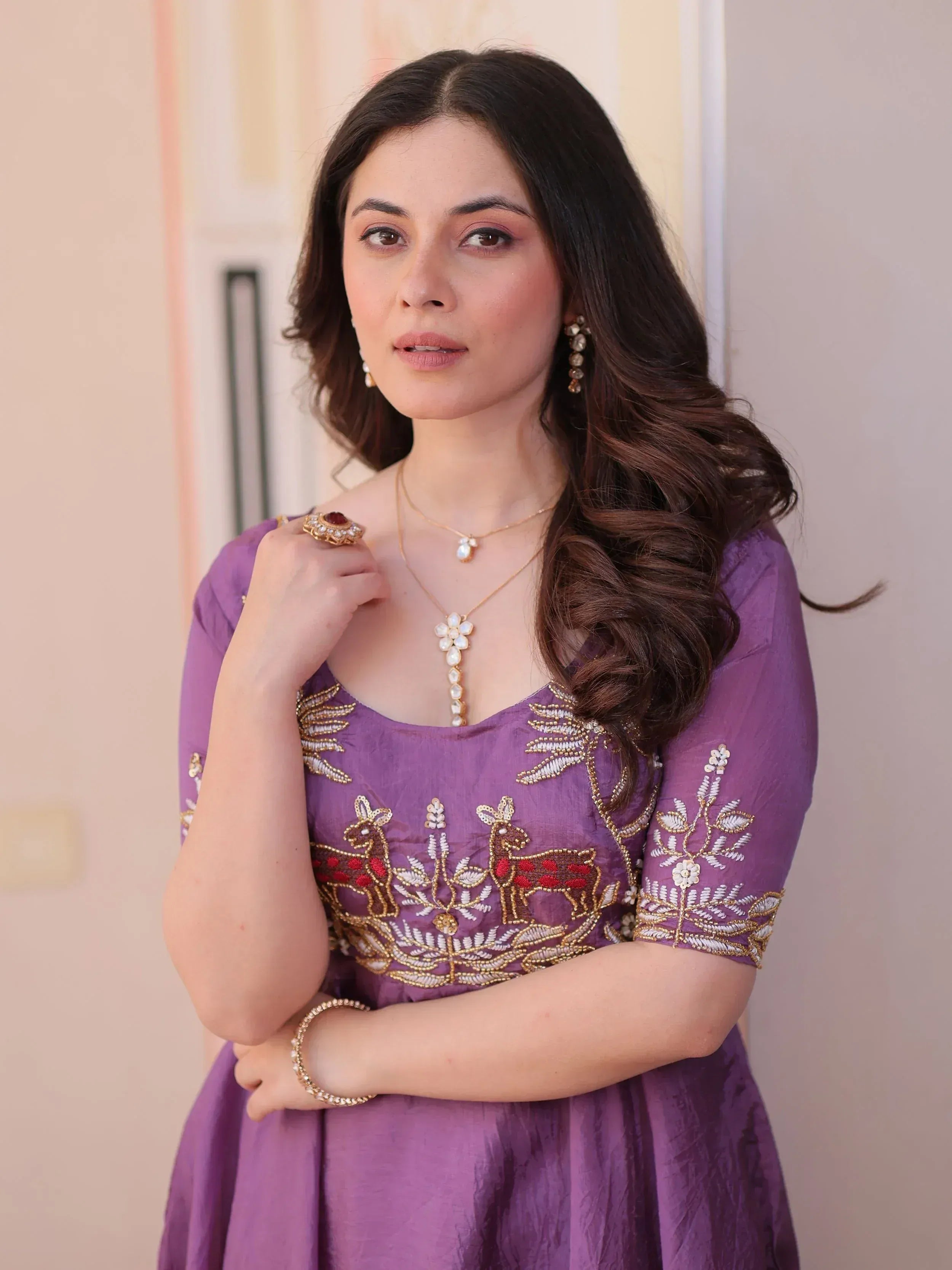 Purple embroidered ethnic gown with deer motif, gold jewelry, and statement ring for festive occasions
