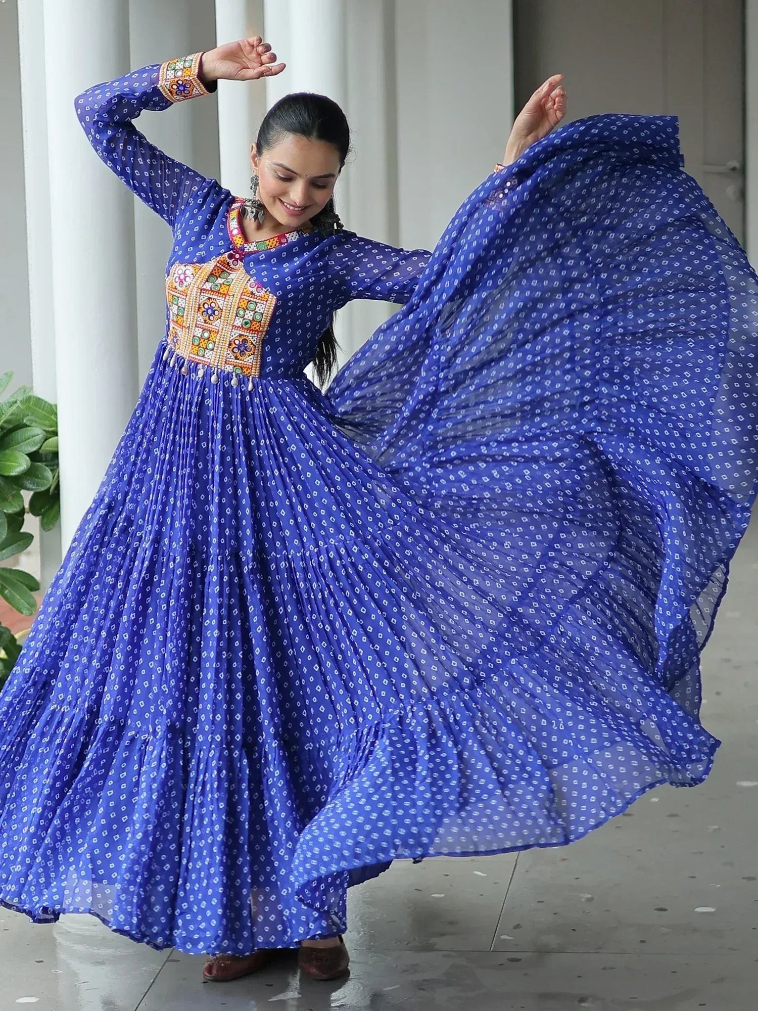 Woman twirling in blue printed ethnic gown with colorful embroidery, perfect for Indian occasions