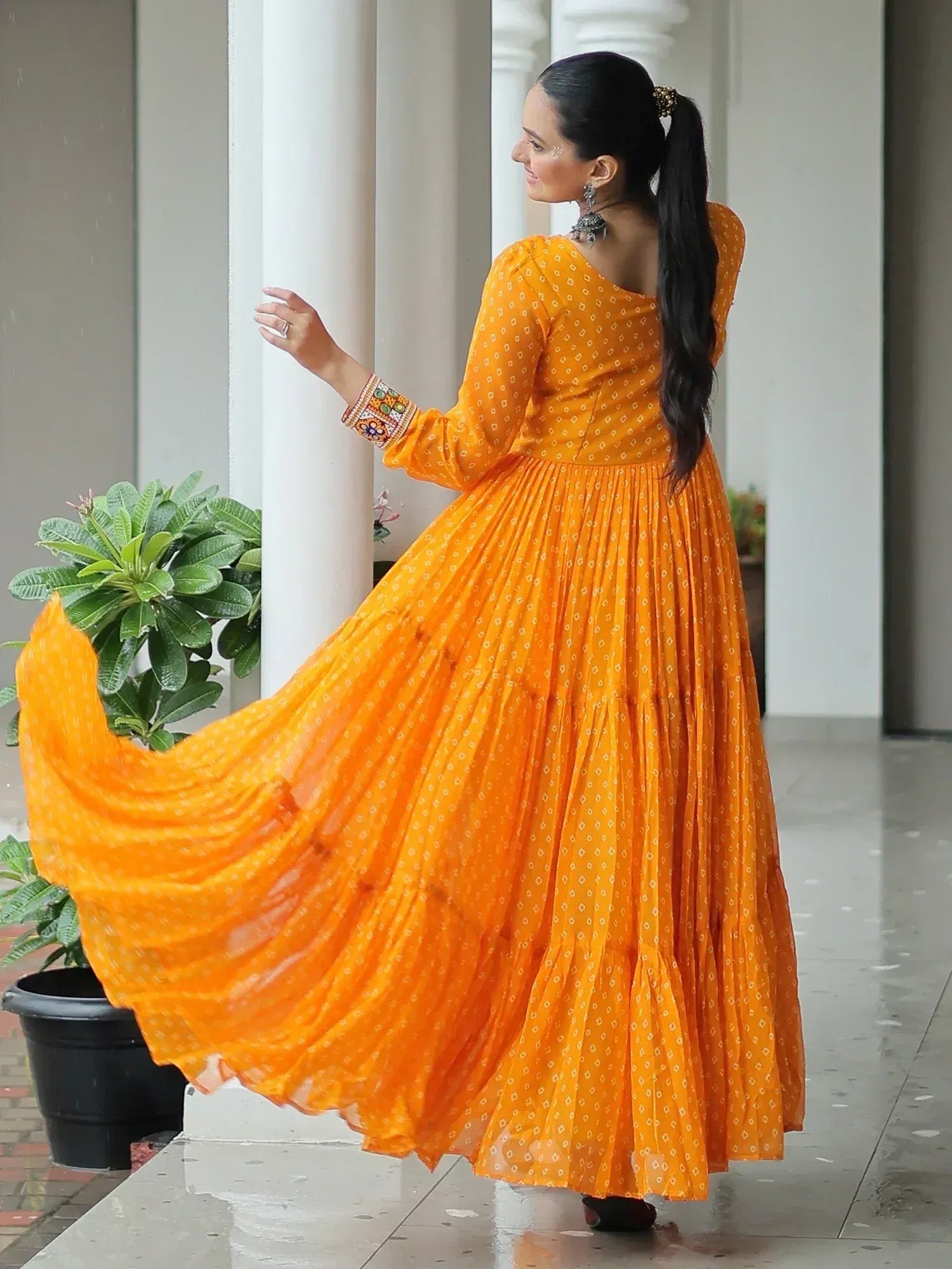 Vibrant orange ethnic gown with printed pattern and embroidered sleeves, perfect for Indian occasions