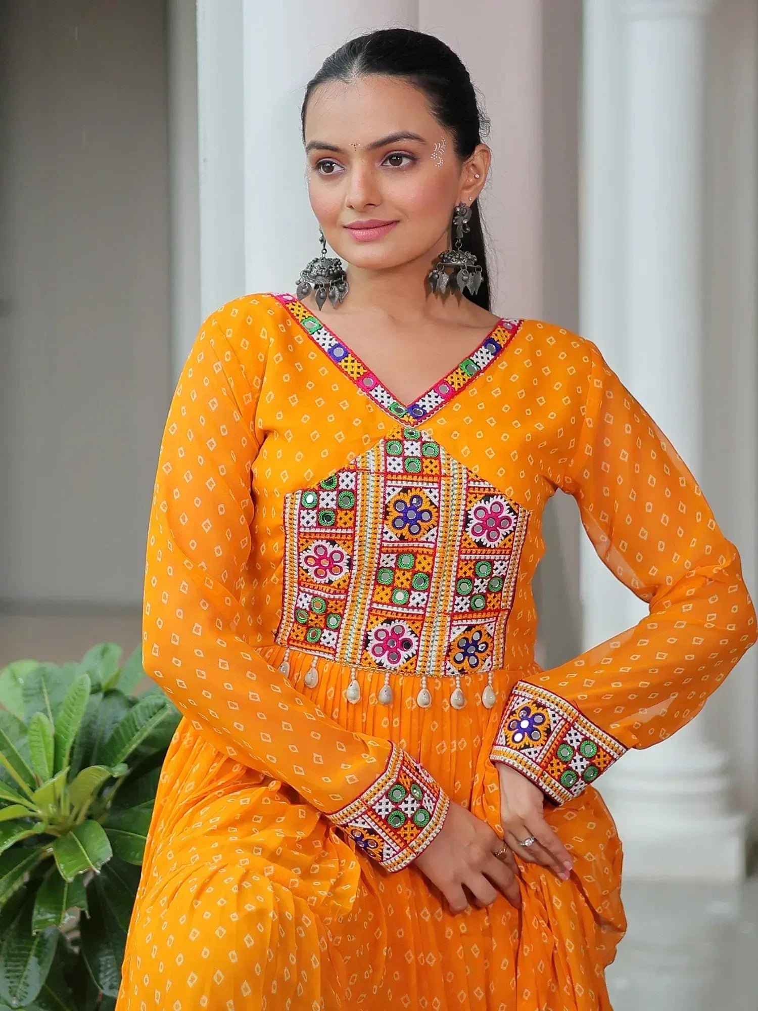 Vibrant orange ethnic gown with mirror work and floral embroidery, perfect for Indian occasions