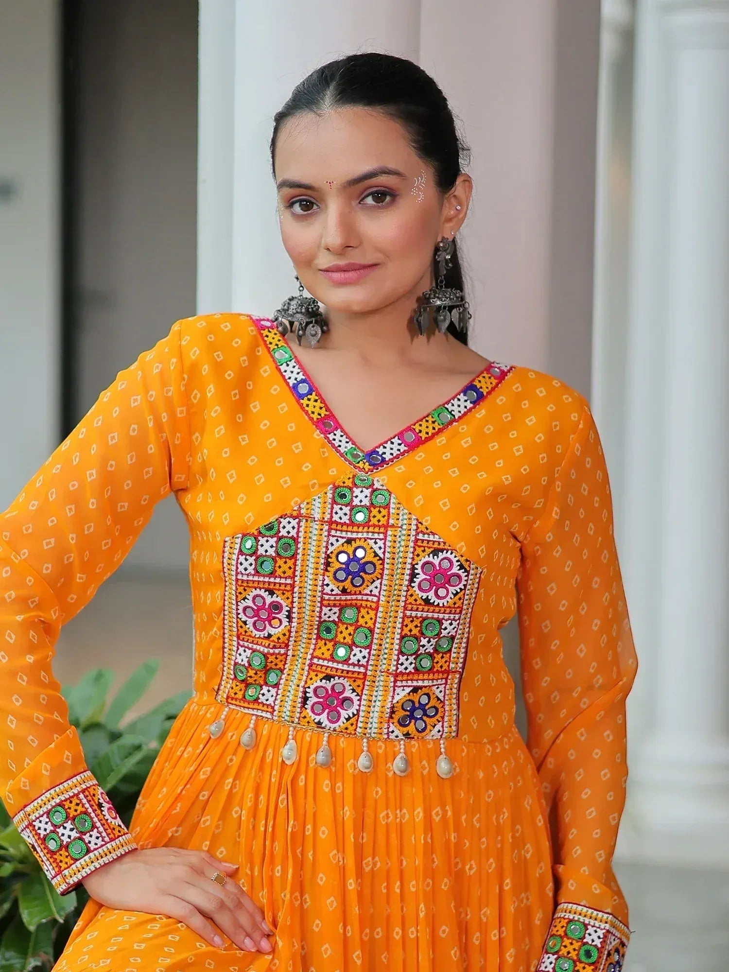 Vibrant orange ethnic gown with mirror work and floral embroidery, perfect for Indian celebrations