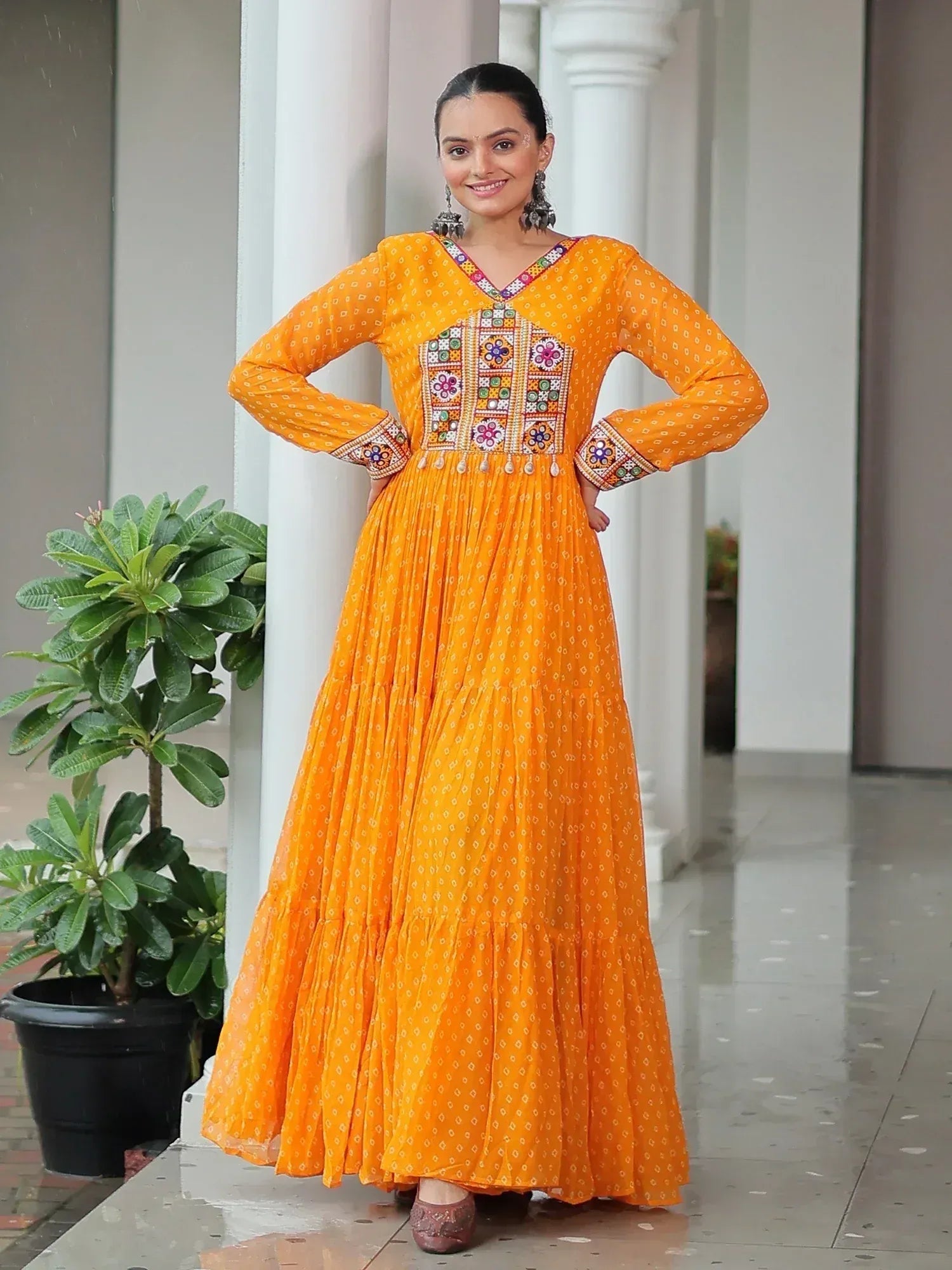 Vibrant orange ethnic gown with mirror work and floral embroidery, perfect for Indian festive occasions.