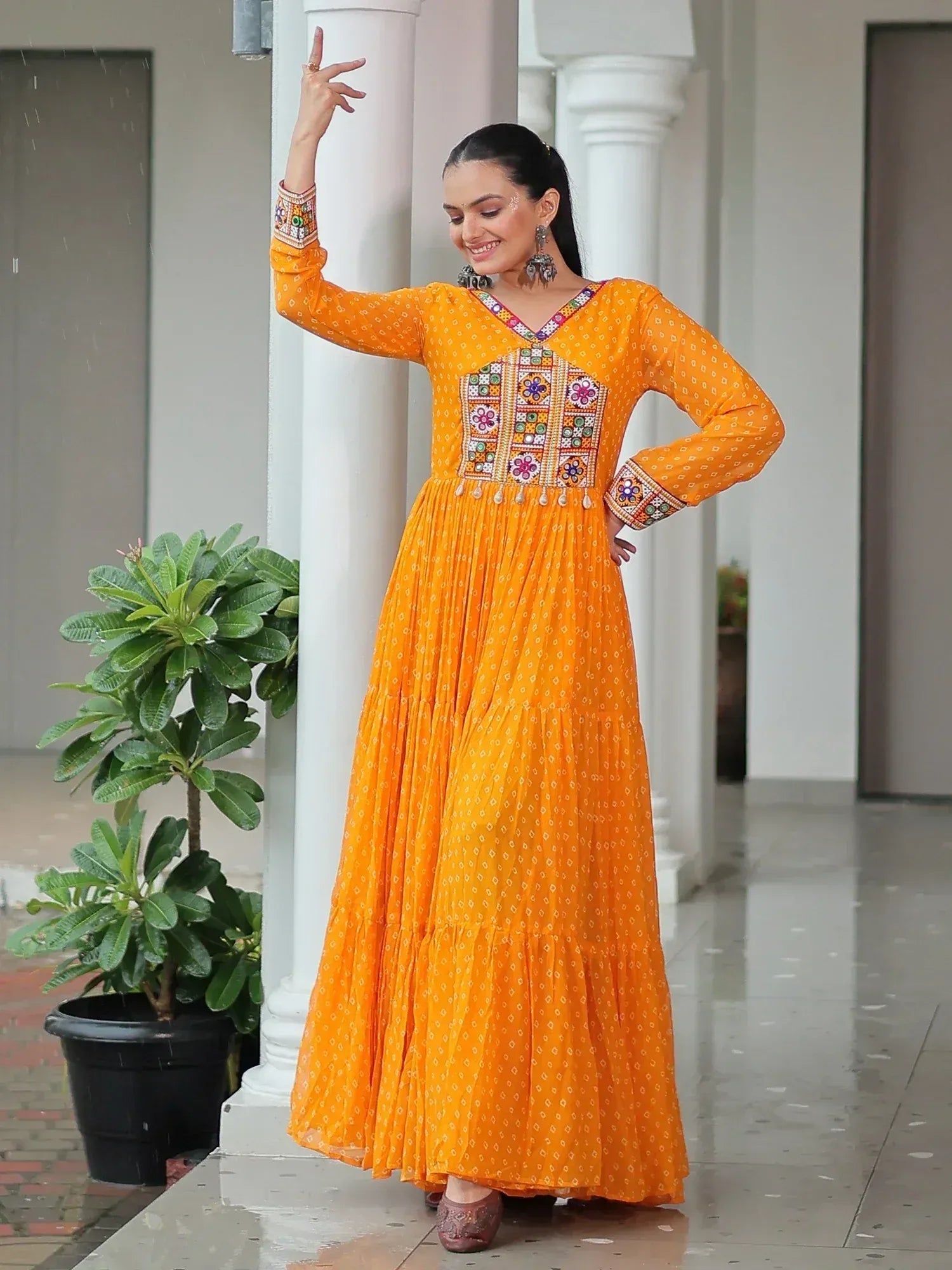 Vibrant orange ethnic gown with mirror work and floral embroidery, perfect for festive occasions
