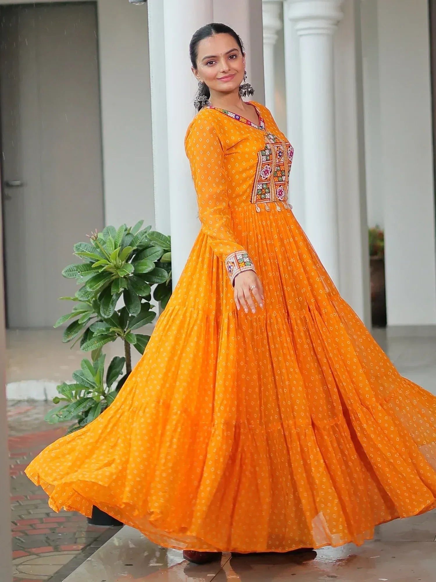 Vibrant orange ethnic gown with mirror work, perfect for festive occasions and Indian celebrations.
