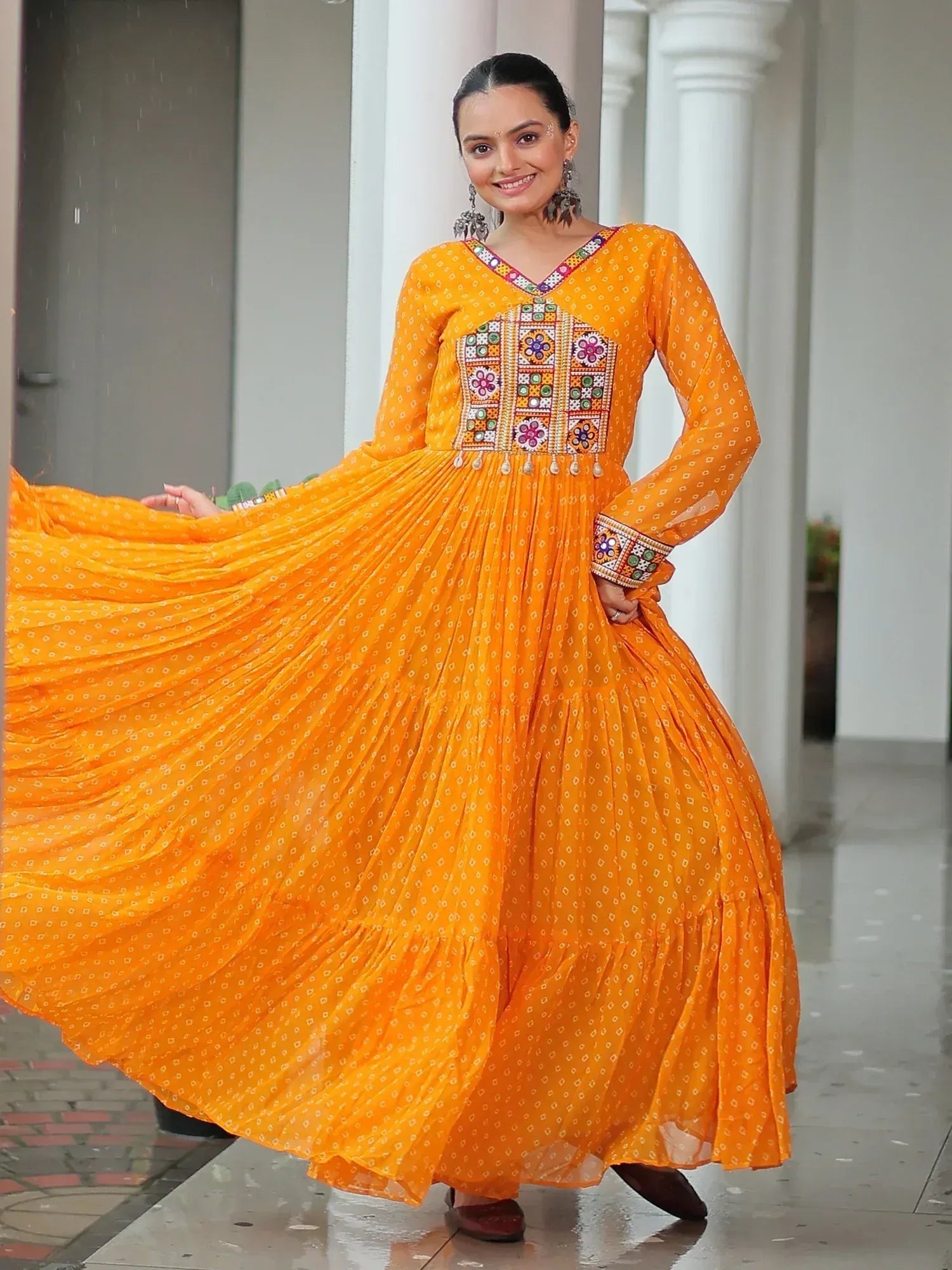 Vibrant orange ethnic gown with mirror work, perfect for Indian celebrations and festive occasions.