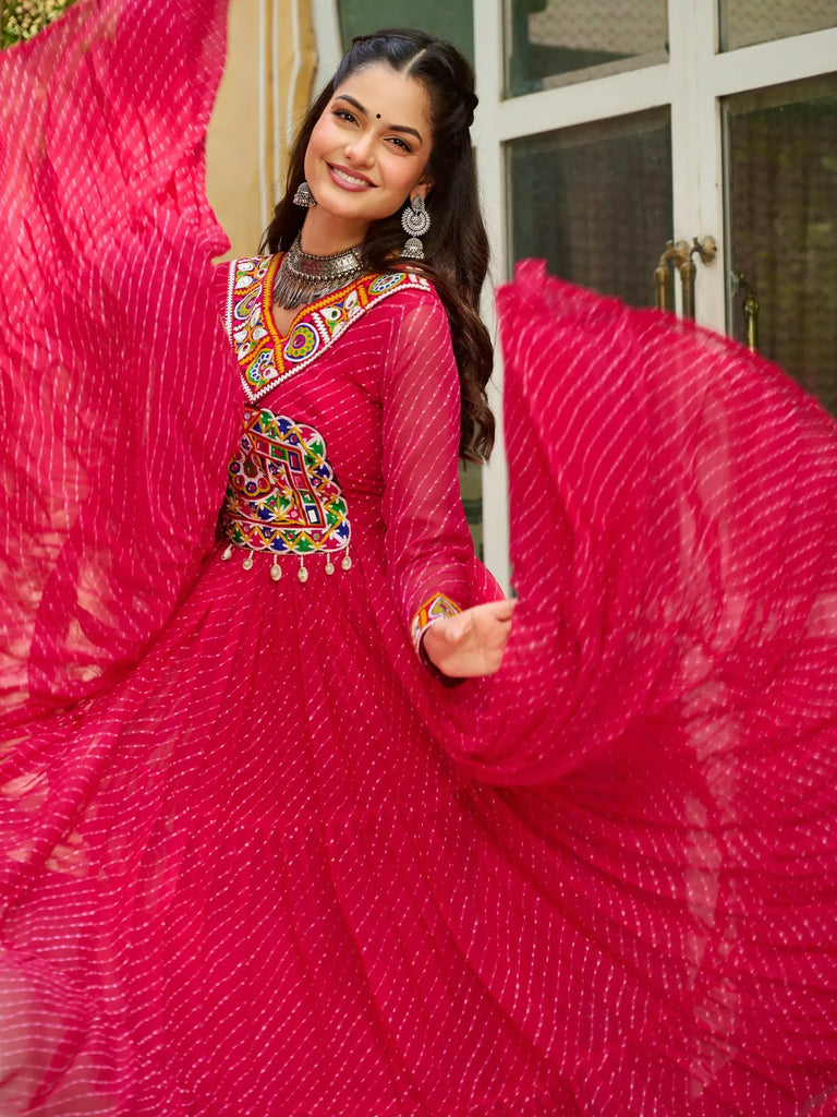 Vibrant pink ethnic gown with colorful mirror work and sheer dupatta, perfect for Indian festivals and weddings.
