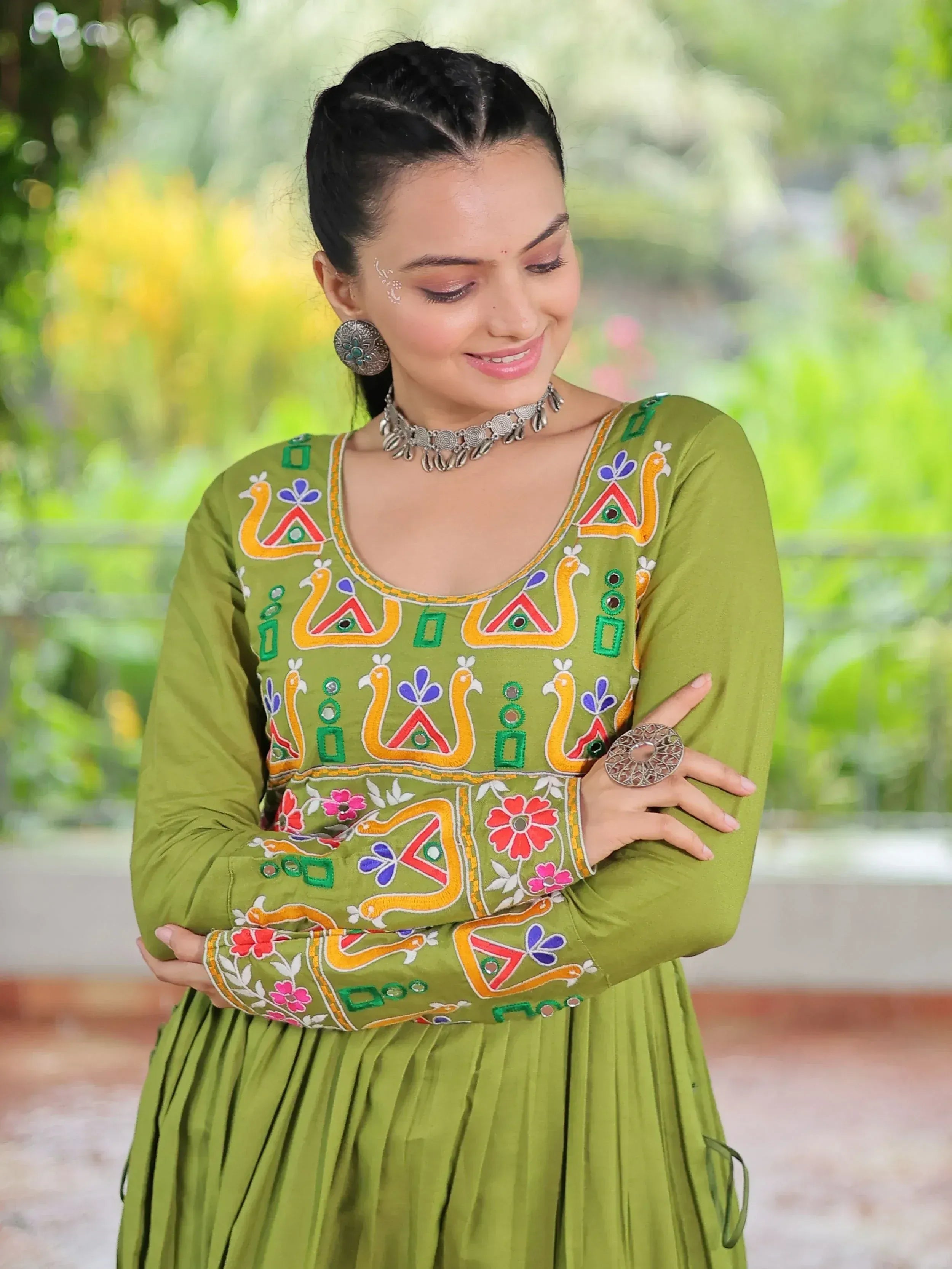 Green embroidered ethnic kurti with floral and peacock motifs, paired with traditional jewelry