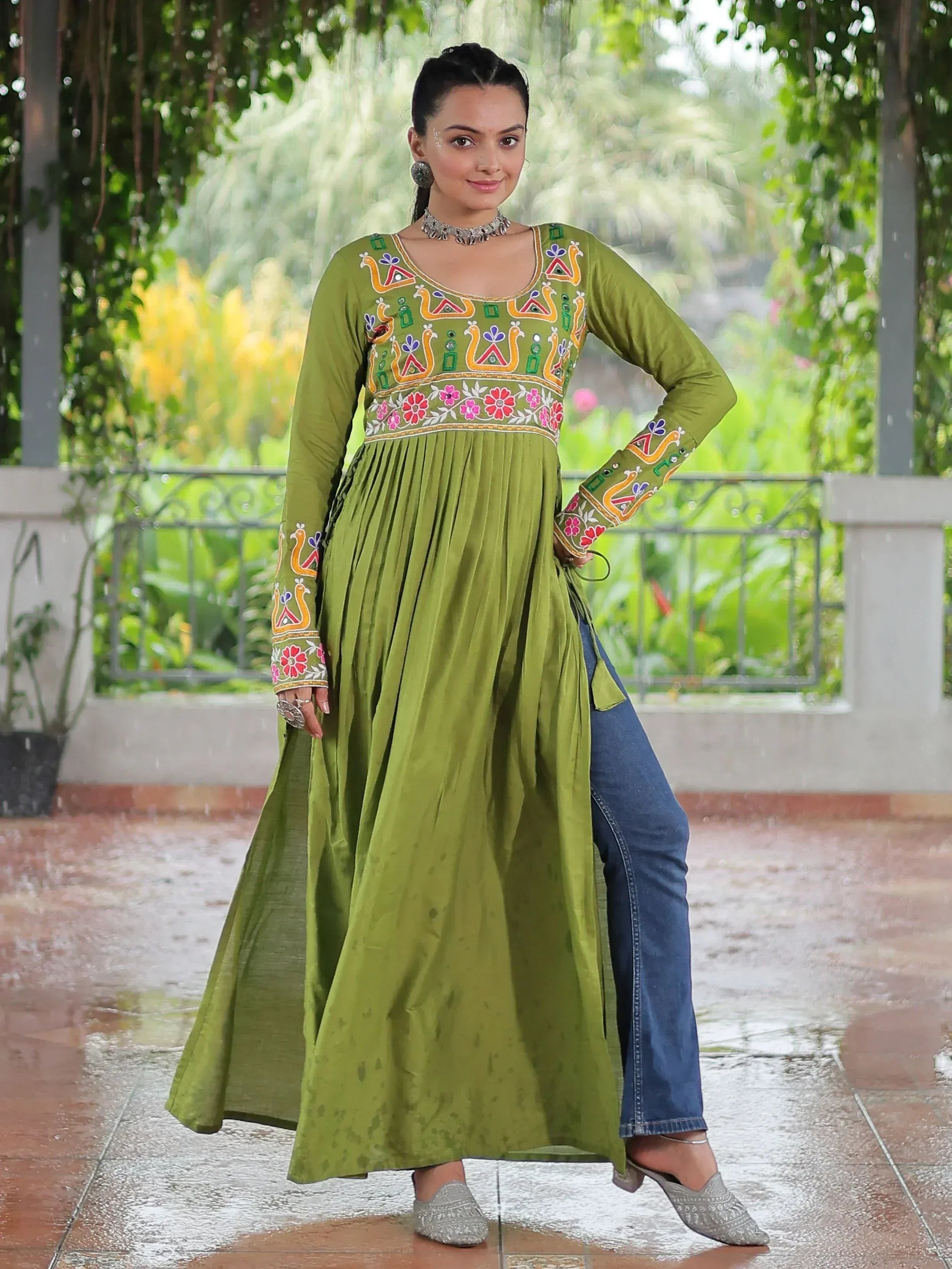 Green embroidered ethnic kurta with floral and peacock motifs, paired with jeans for a fusion look.