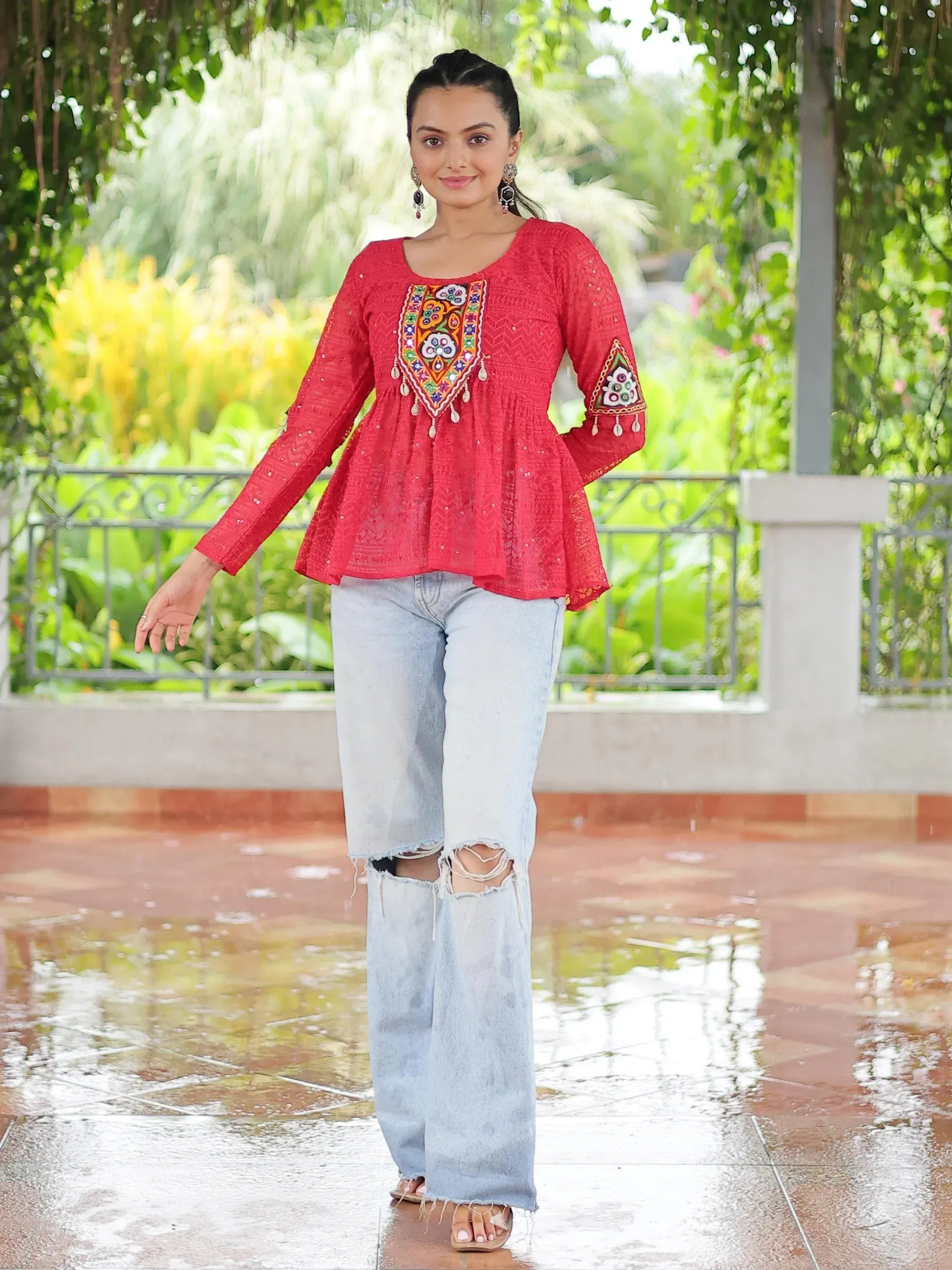 Red embroidered ethnic top with bell sleeves paired with ripped denim jeans, perfect for casual Indian wear.