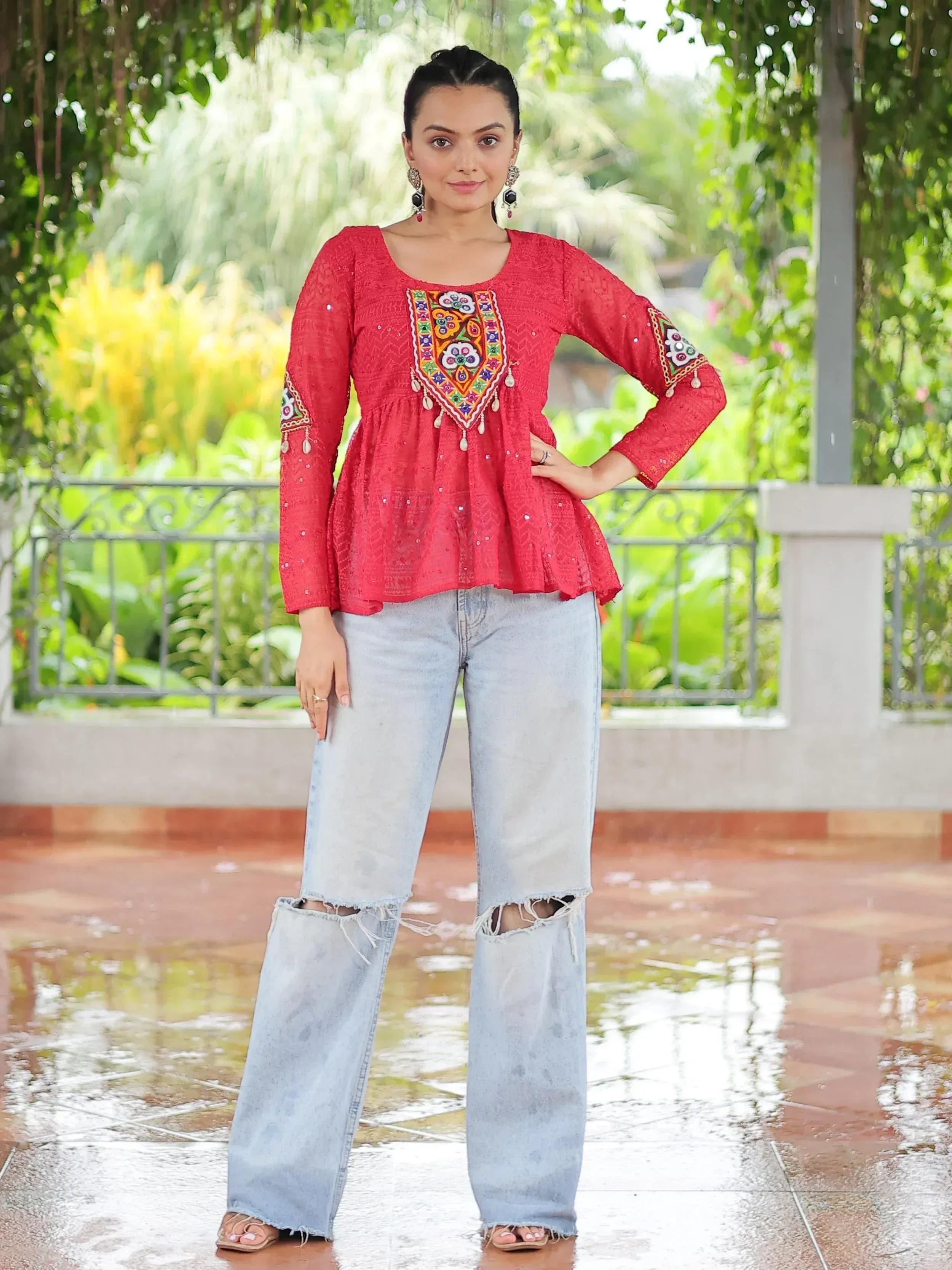 Red embroidered ethnic top with bell sleeves paired with ripped denim jeans, perfect for casual Indian wear.