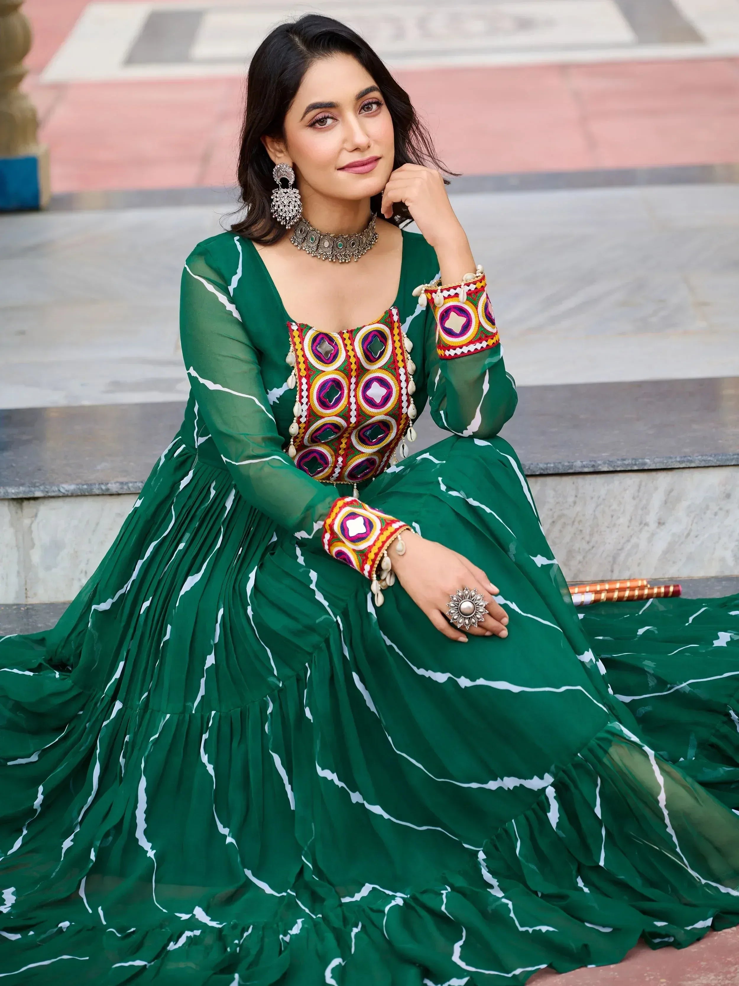 Green ethnic gown with mirror work and white print, paired with traditional jewelry for festive occasions
