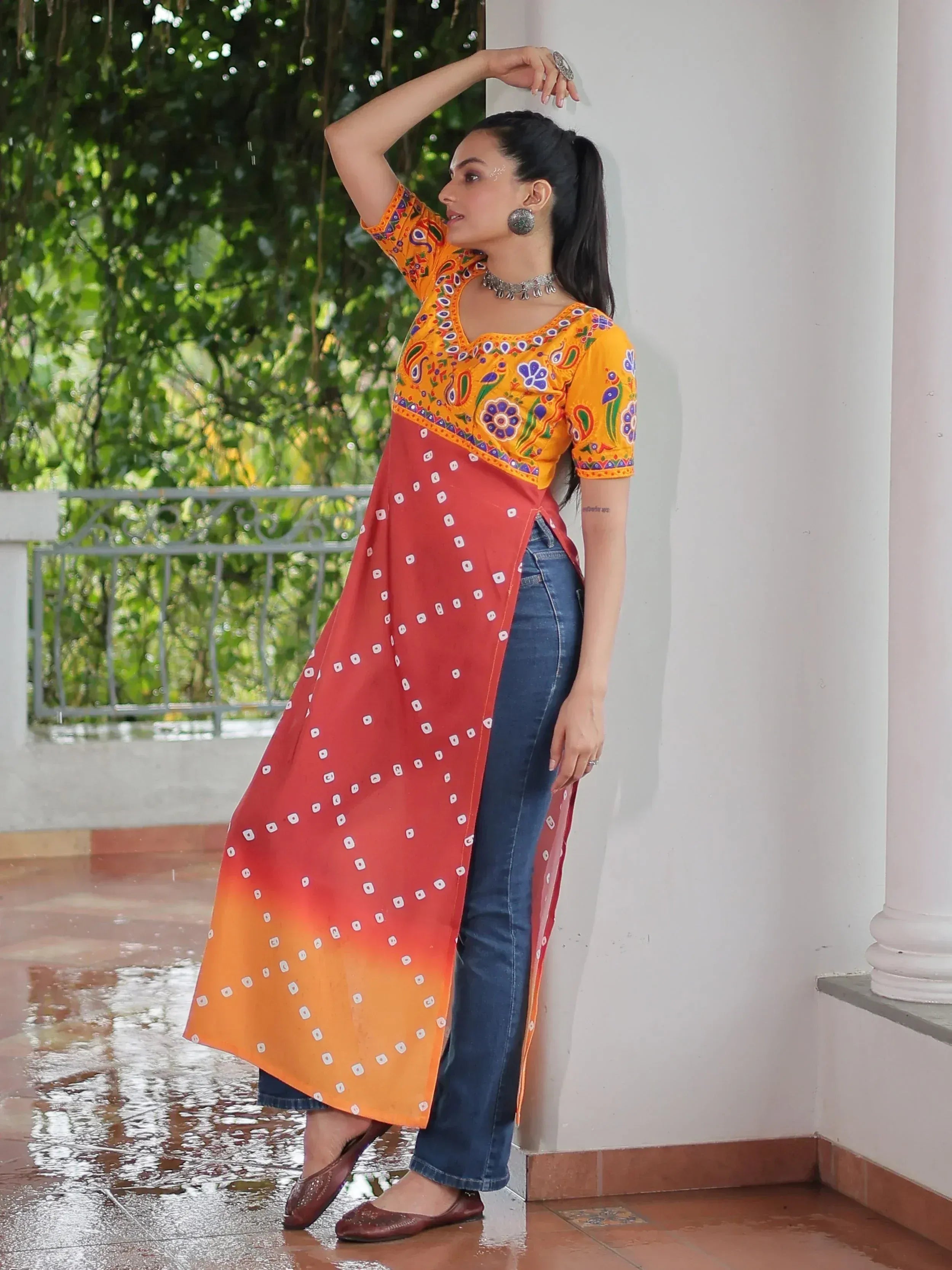 Woman in vibrant orange and red printed ethnic kurta with jeans, perfect for Indian festive wear
