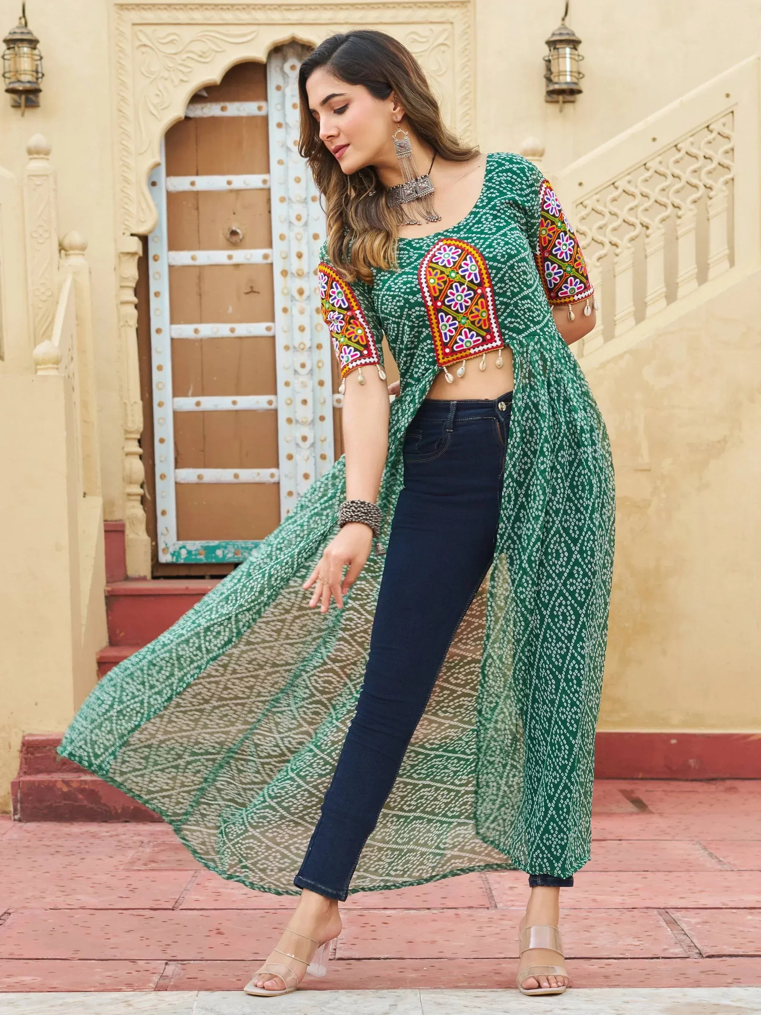 Green embroidered ethnic crop top with floral mirror work, paired with jeans and sheer drape, perfect for Indian fashion.