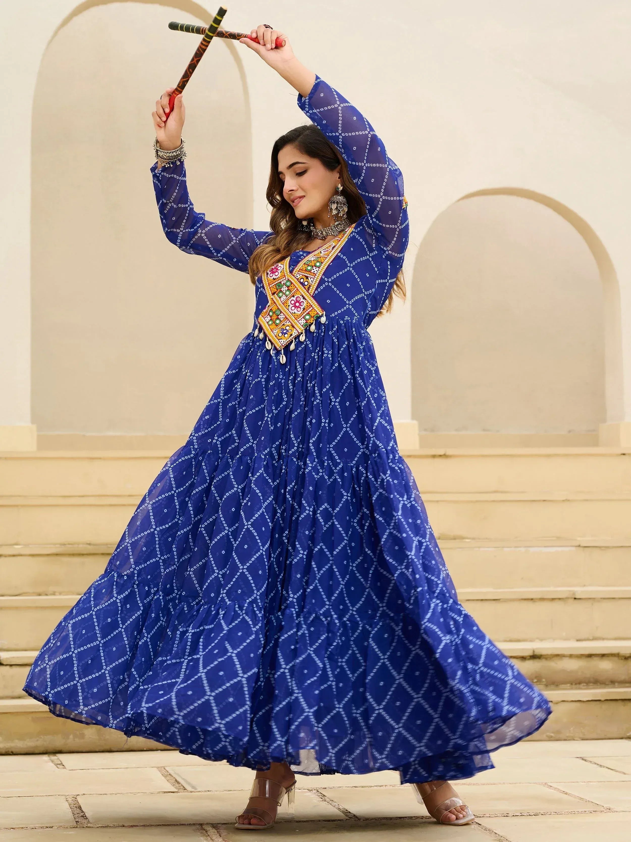 Woman in blue ethnic gown with mirror work dancing with dandiya sticks