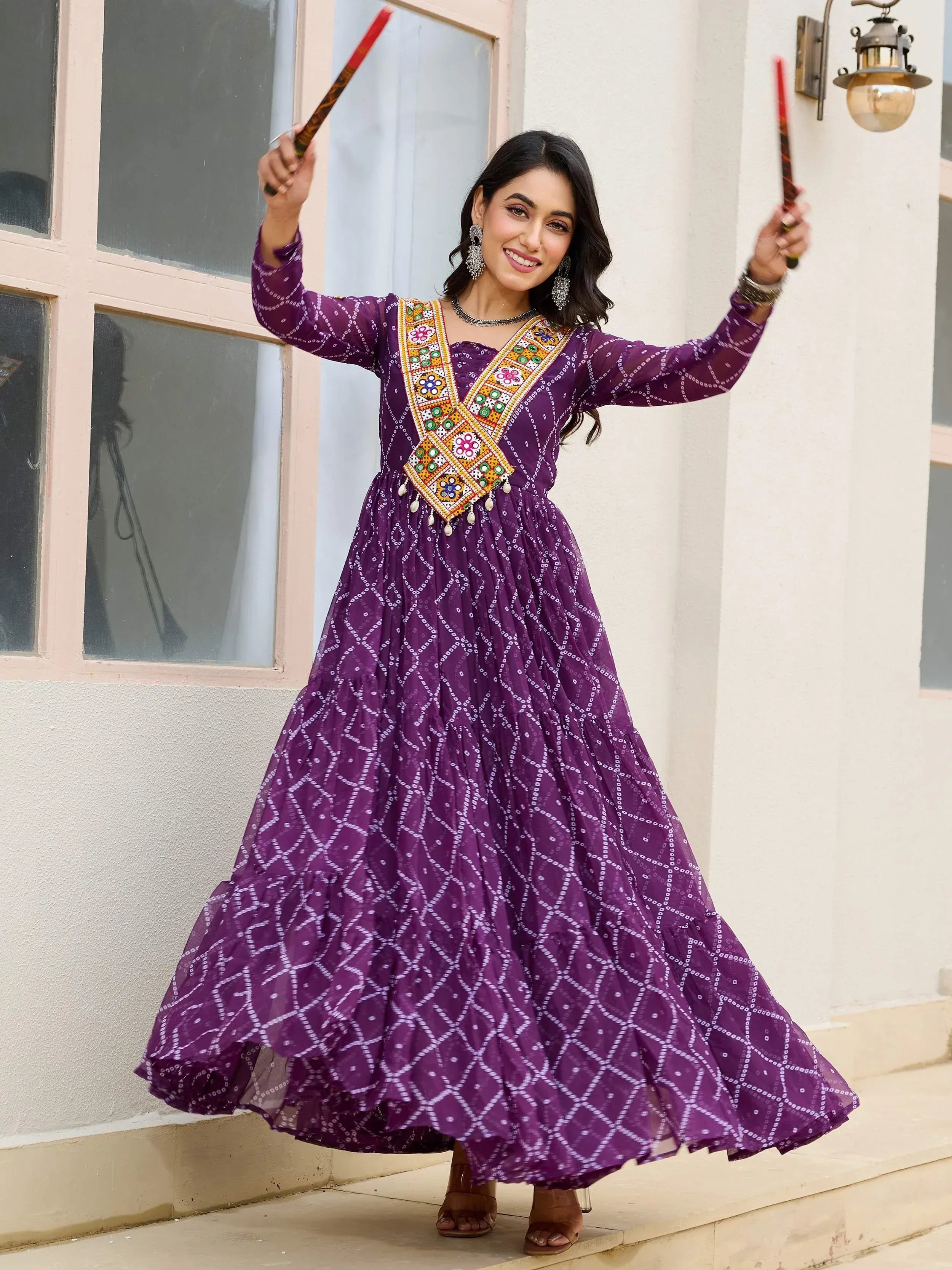 Woman in purple ethnic gown with mirror work, dancing with dandiya sticks, perfect for festive occasions