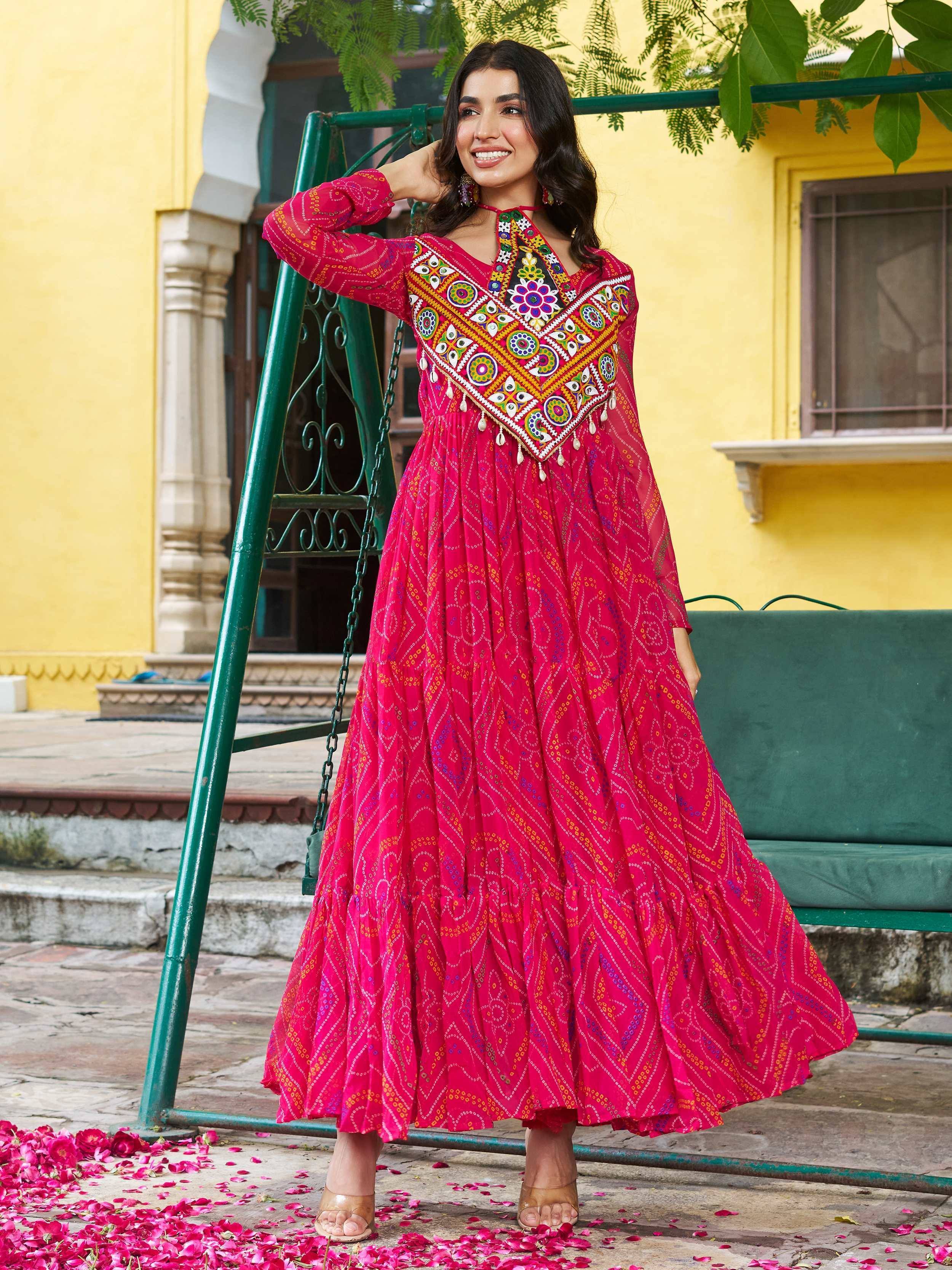 Vibrant pink ethnic gown with colorful mirror work and embroidery, perfect for Indian festive occasions.