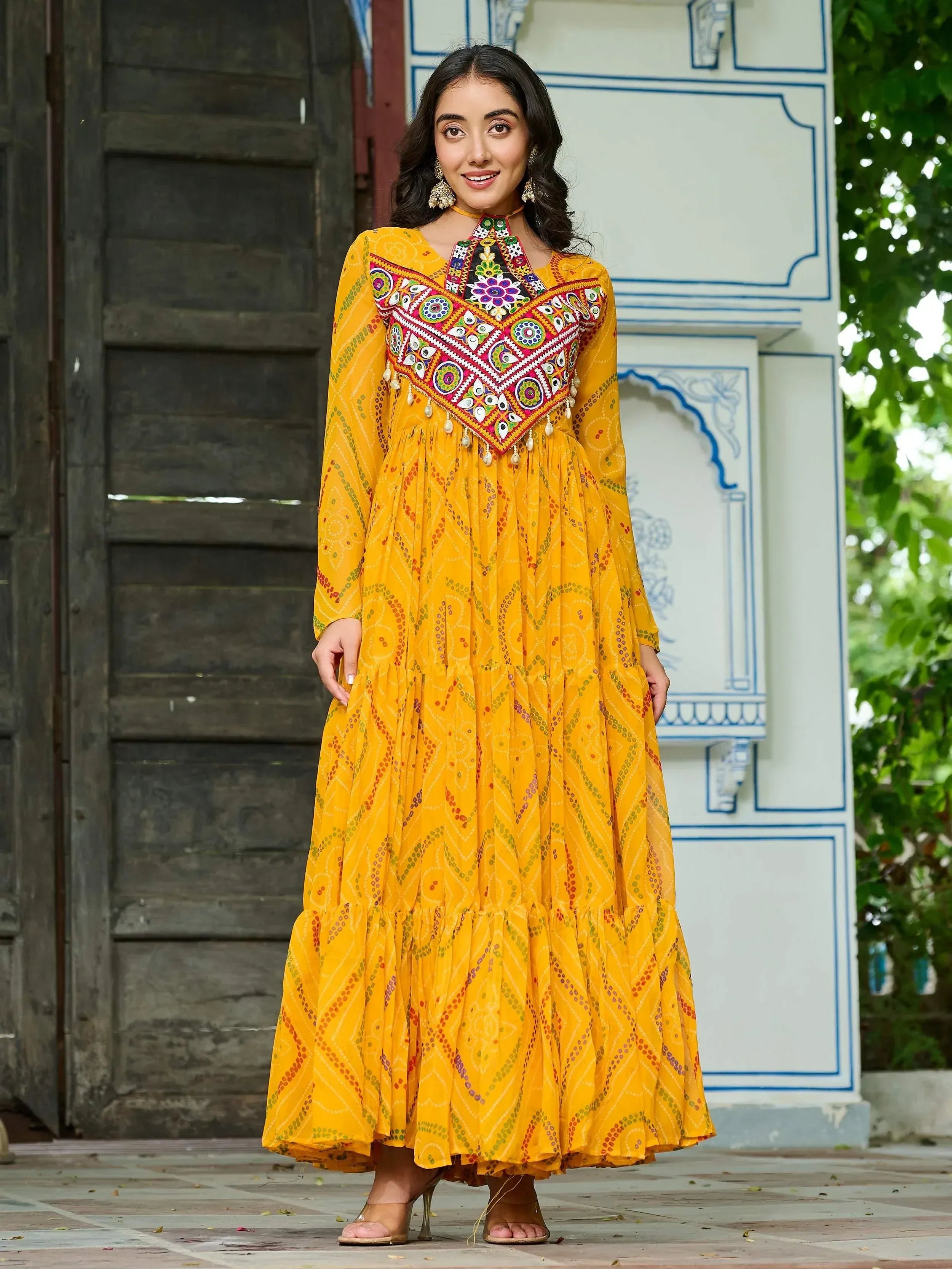 Yellow ethnic gown with mirror work and printed patterns, perfect for festive occasions