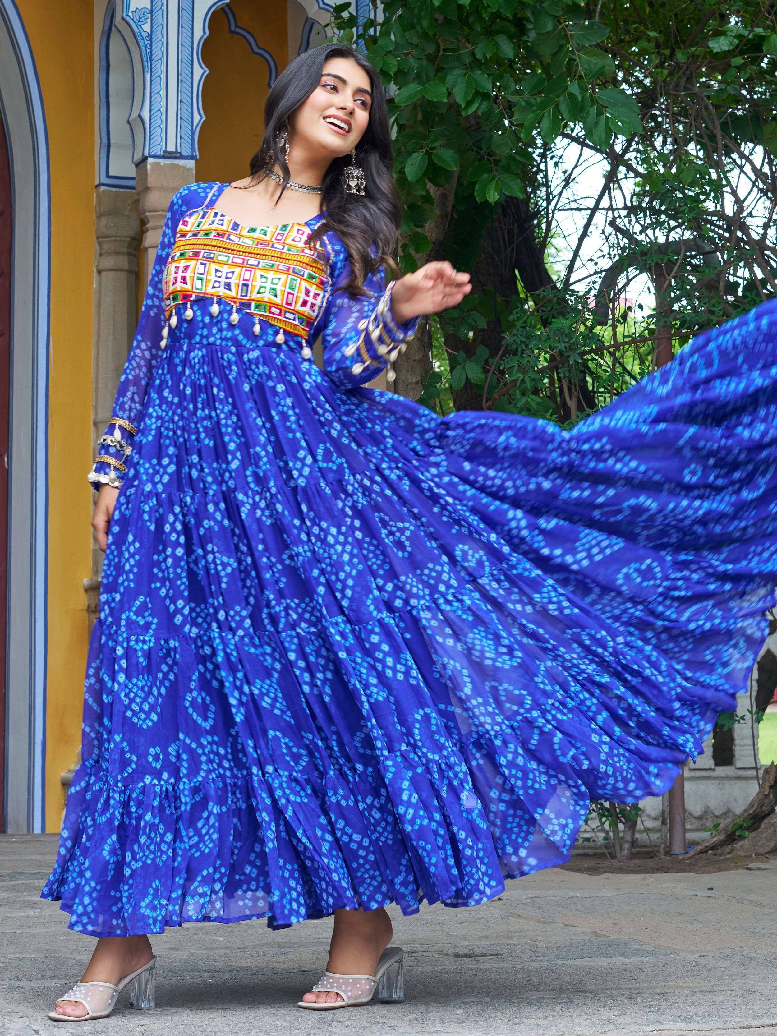 Woman in vibrant blue ethnic gown with colorful embroidery, twirling outdoors near traditional archway