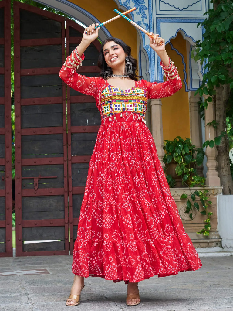 Woman in vibrant red ethnic gown with mirror work, dancing with dandiya sticks against traditional Indian architecture