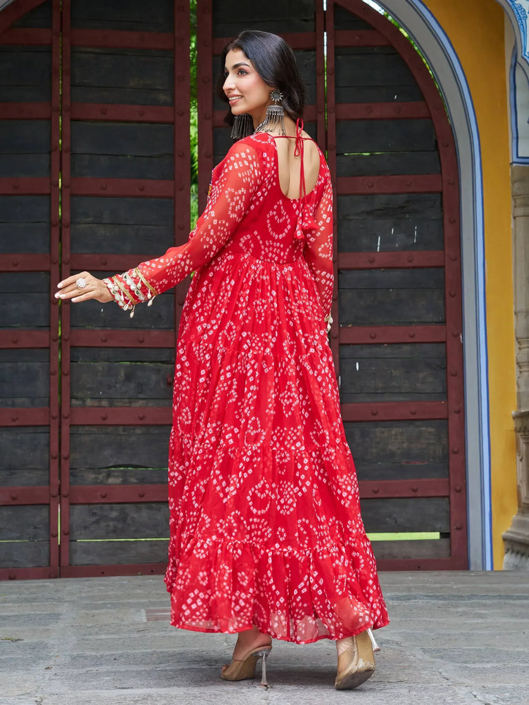 Red printed ethnic gown with back tie, long sleeves, and tiered skirt, styled with statement jewelry