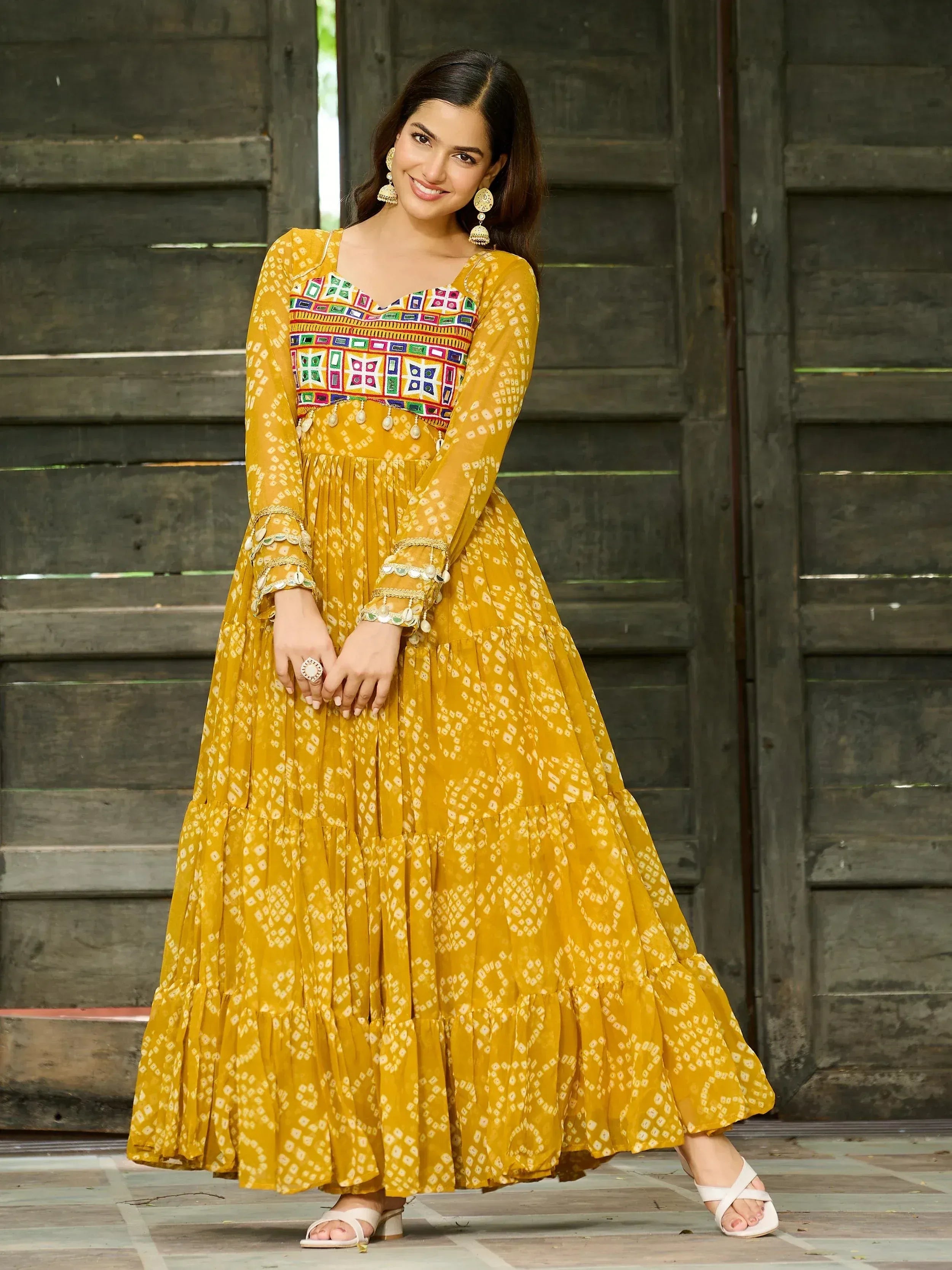 Yellow ethnic gown with mirror work and tiered skirt, perfect for Indian occasions
