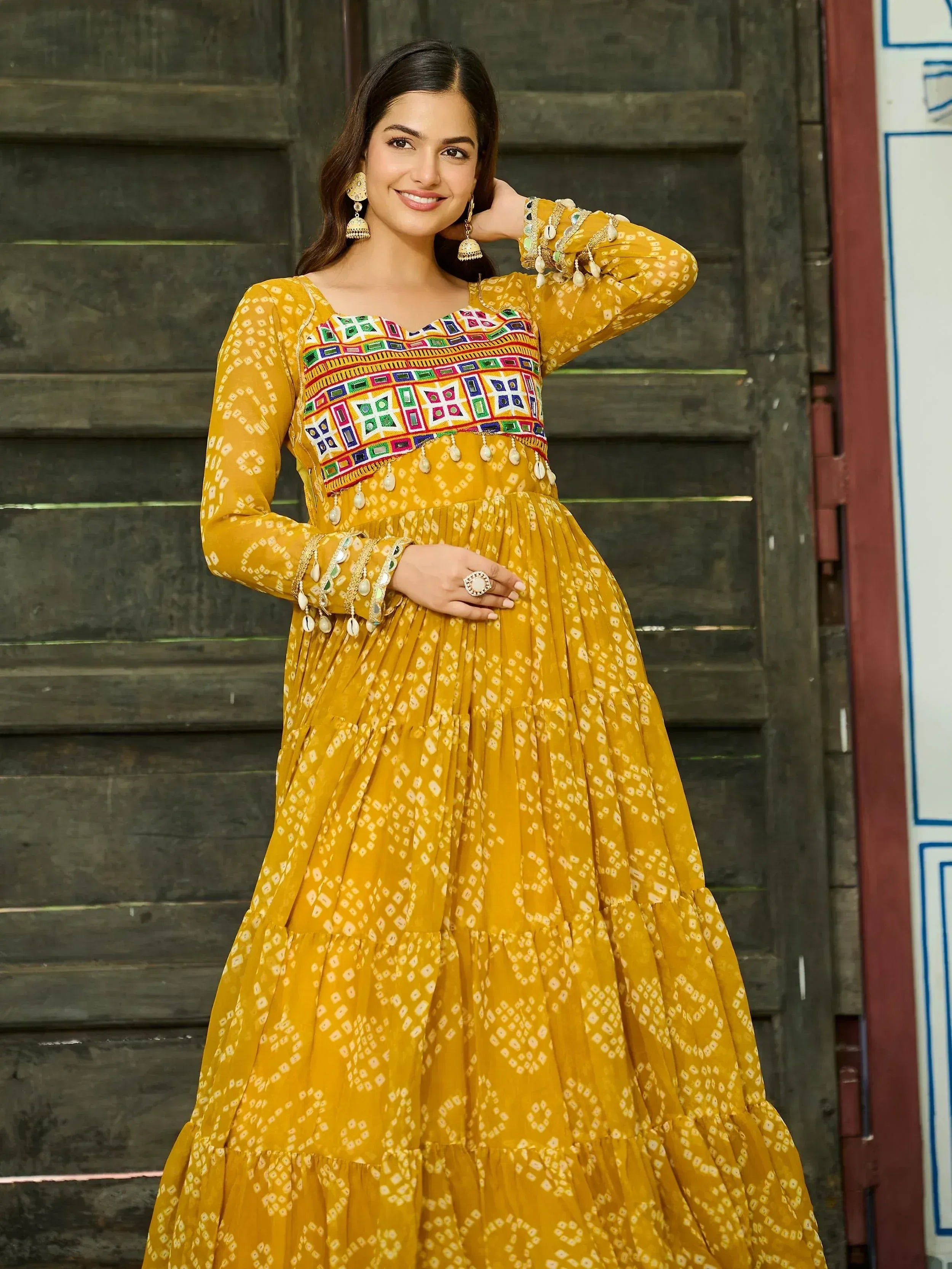 Yellow ethnic gown with mirror work and tiered skirt, perfect for Indian festive occasions