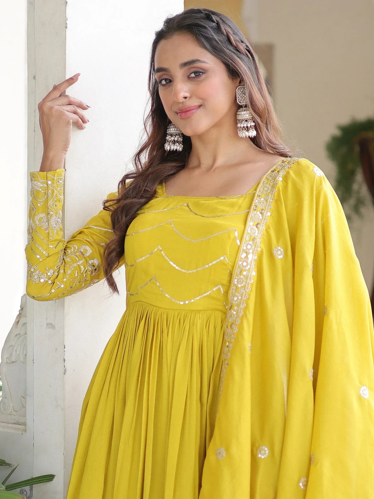 Yellow ethnic gown with embroidery and pleated skirt, styled with jhumka earrings for Indian wear