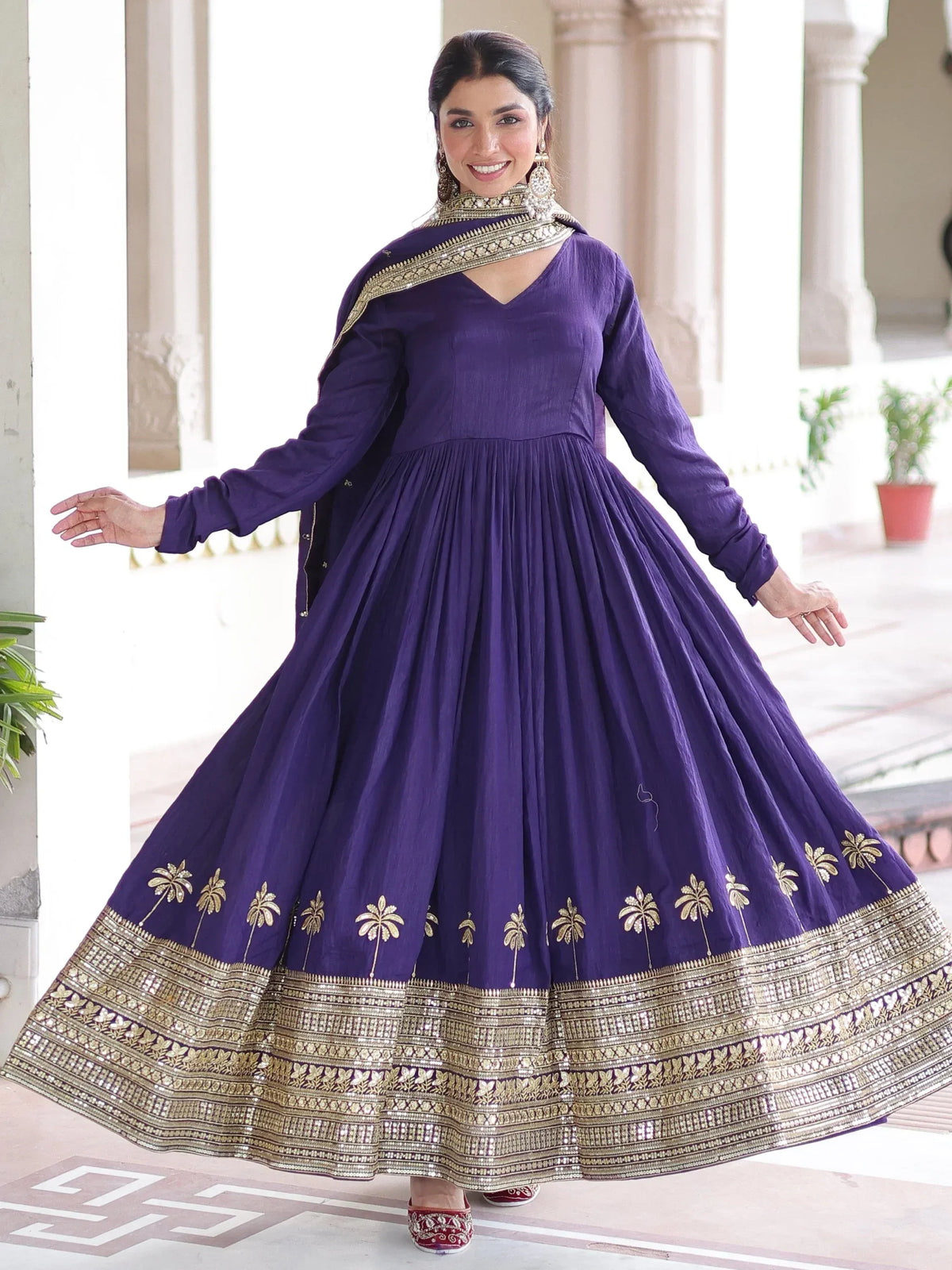 Woman wearing a purple Anarkali suit with gold embroidery and a matching dupatta
